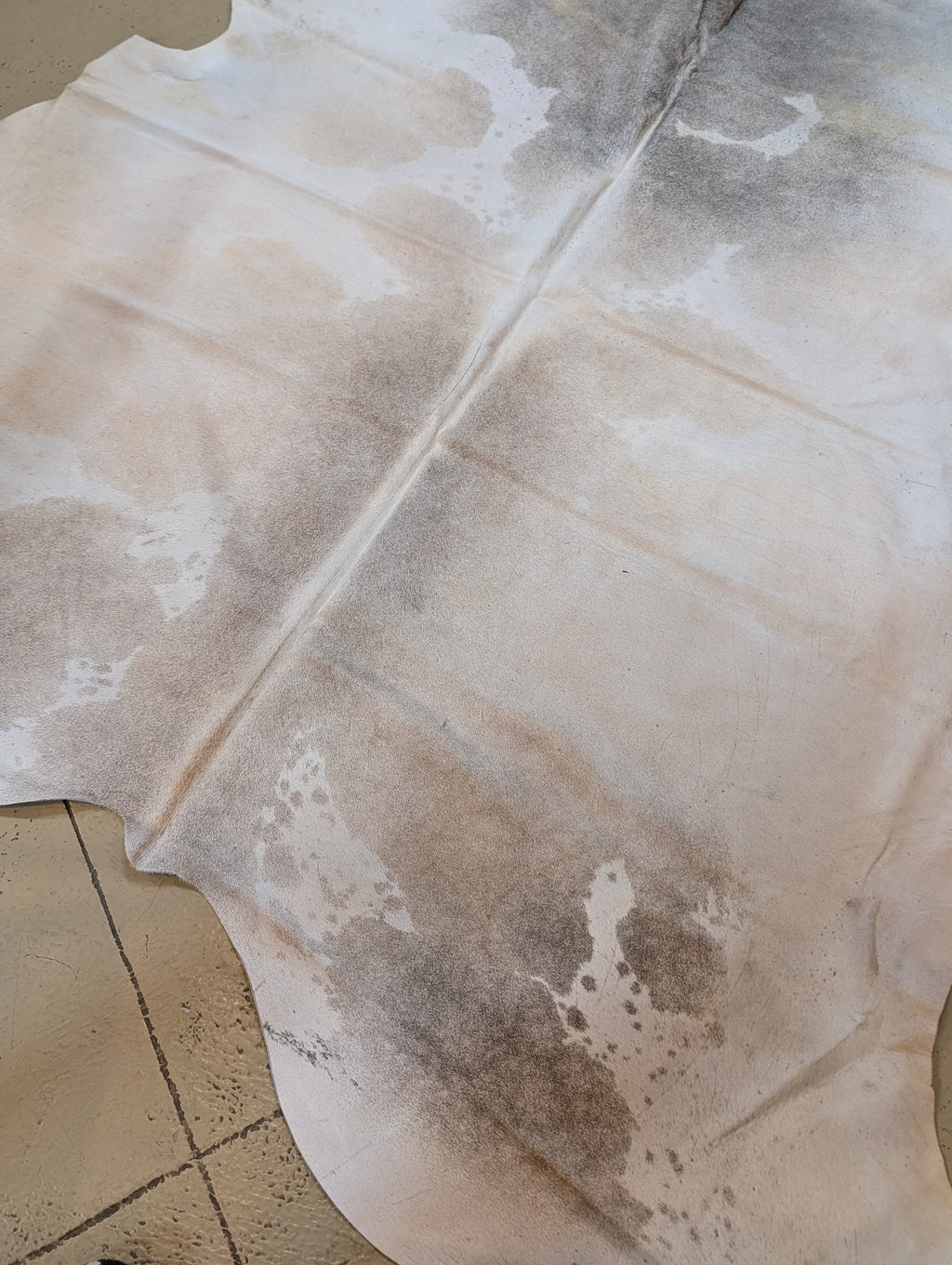 Cowhide Silver & tan rug on a tile floor
