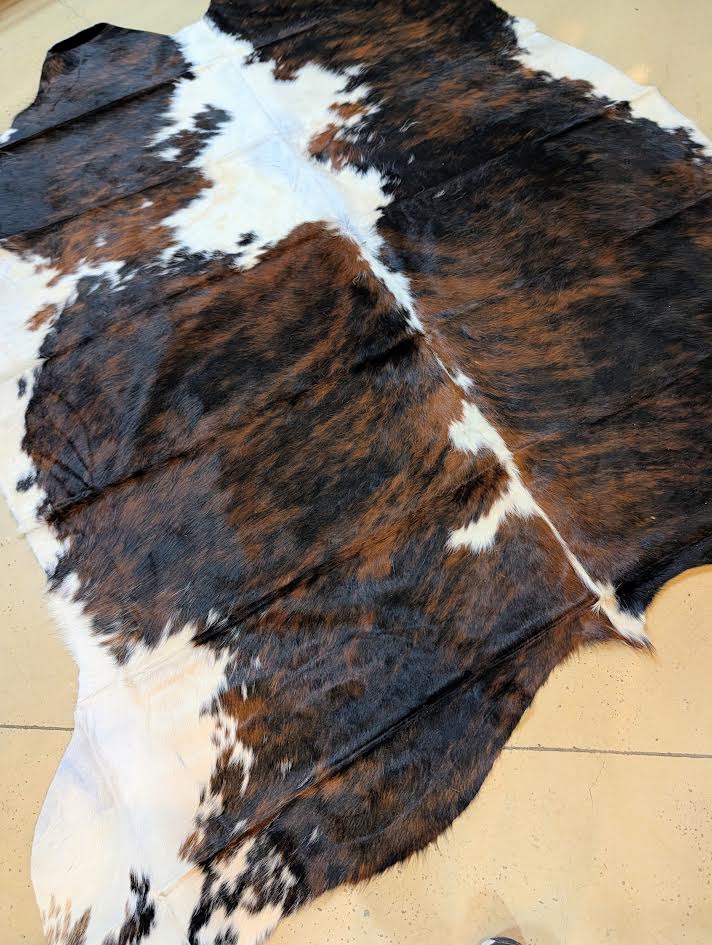 Tri-color Cowhide rug on a tan floor