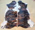 Cowhide rug with brown, black, and white pattern on a beige floor.