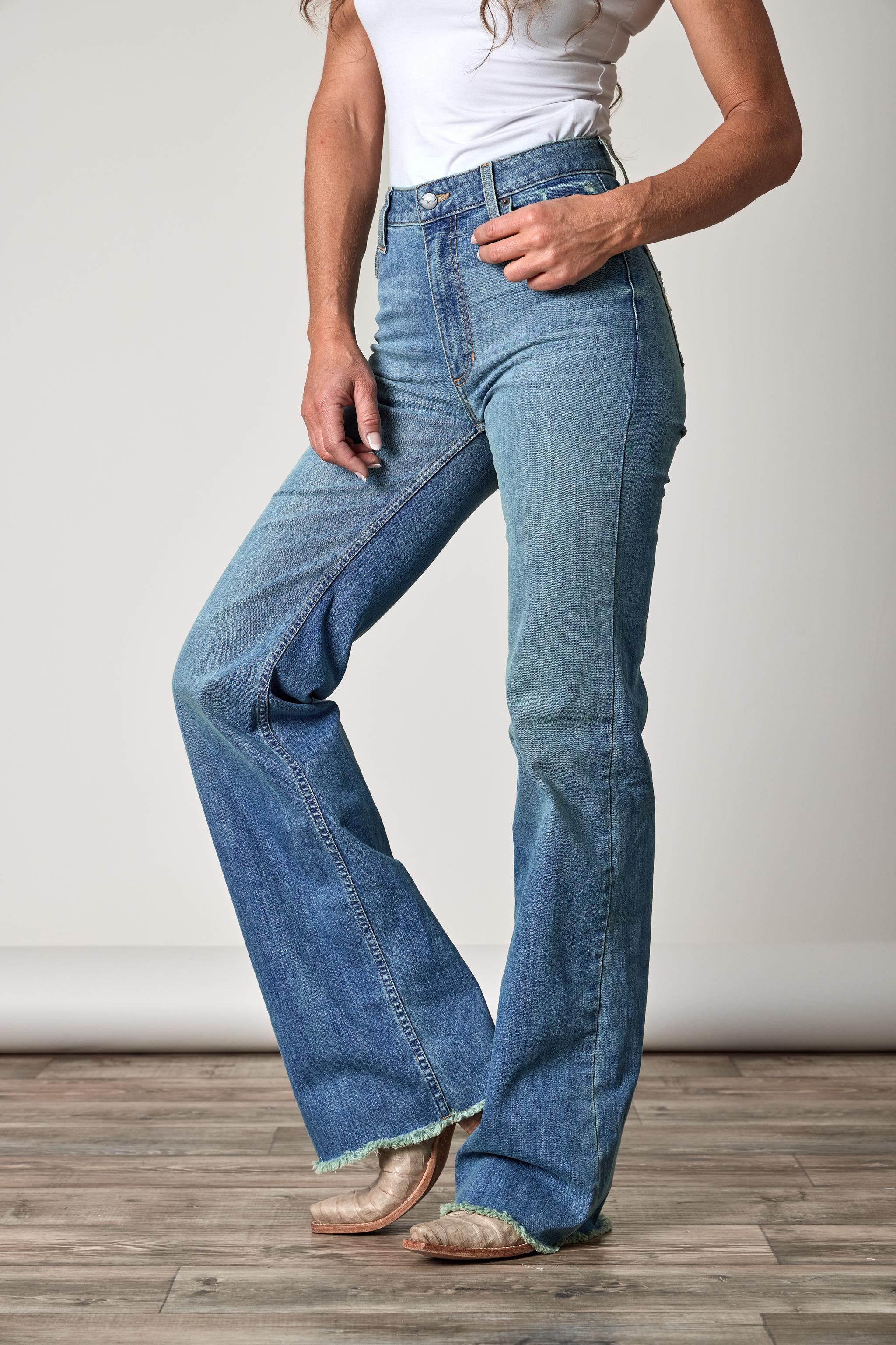 Person wearing blue flared jeans on a plain background