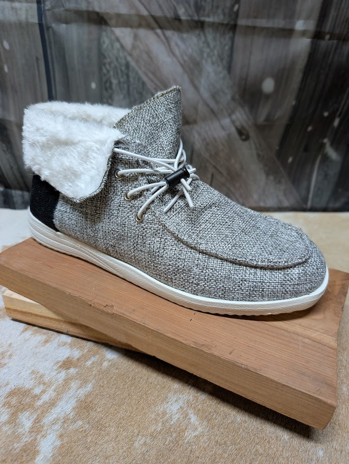 Gray textured shoe with white fur lining on a wooden block against a blurred background