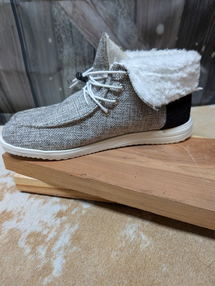 Textured gray shoe with white fur lining on a wooden surface