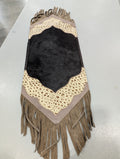 A beige and black cowhide fringe table runner with a solid pattern and tassel detailing.