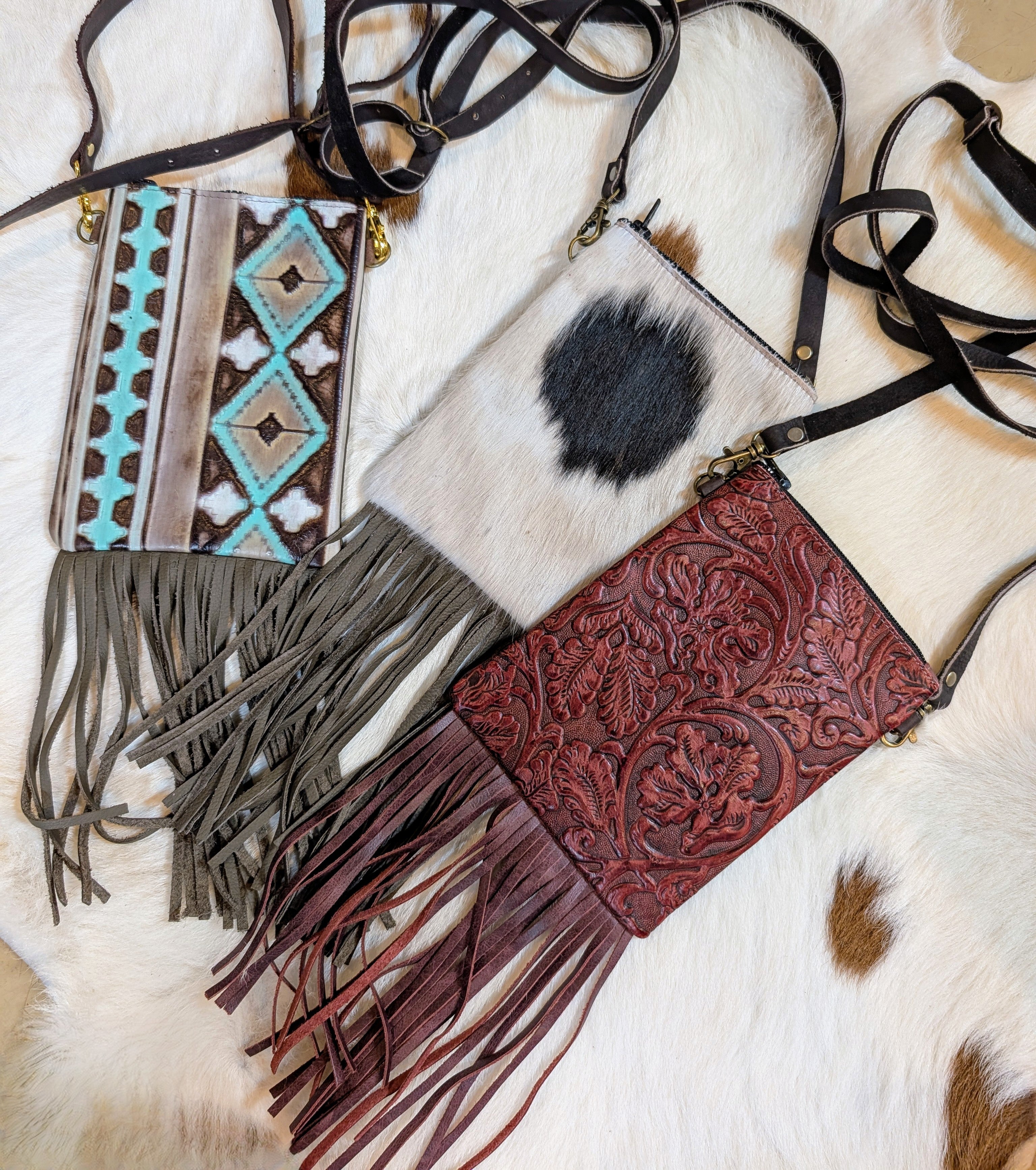 Collection of leather handbags with fringe and intricate designs on a fur surface