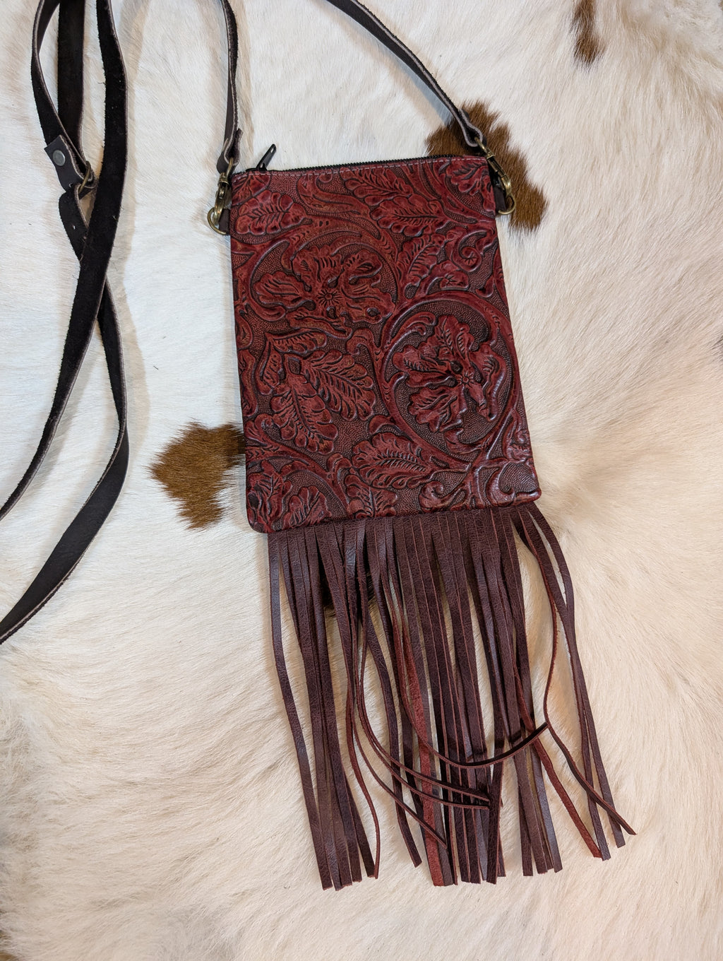 Tooled western design genuine leather fringe crossbody bag with intricate floral patterns and zipper closure.