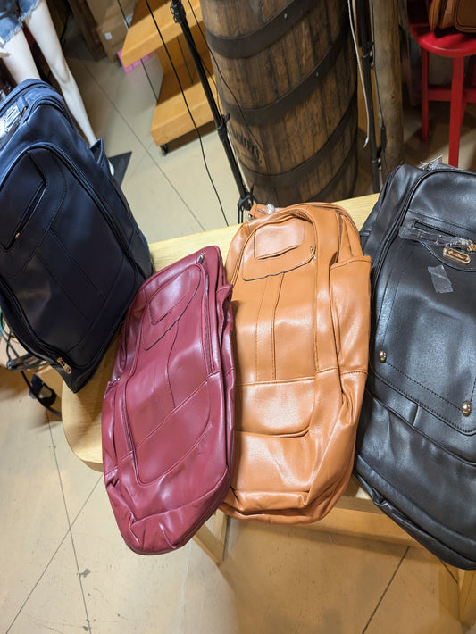 Montana West Frontier Carry-All Backpack in PVC leather with multiple compartments, displayed on rustic background