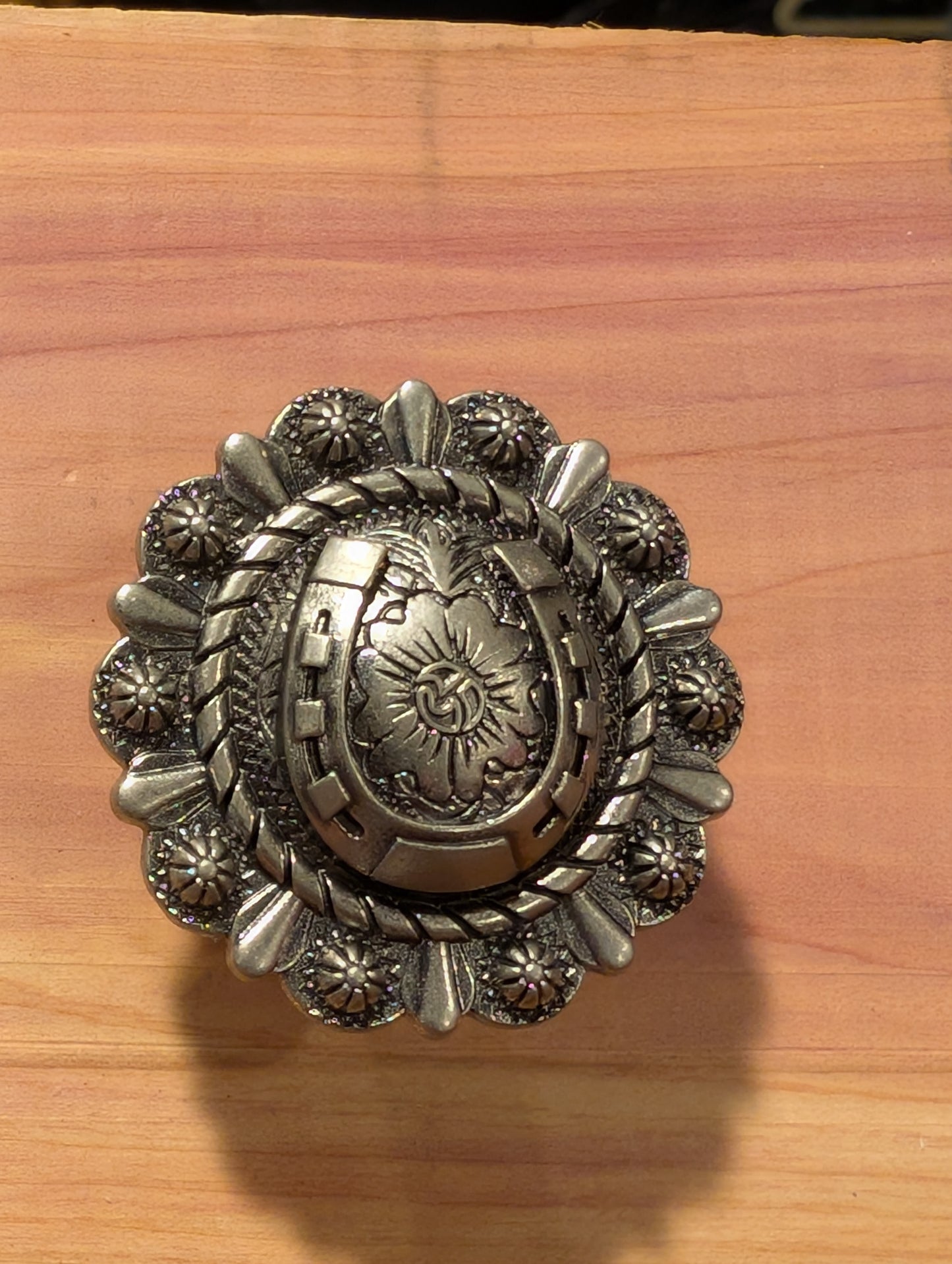 Western-style cabinet knobs featuring antique finishes and unique western patterns on wood table.