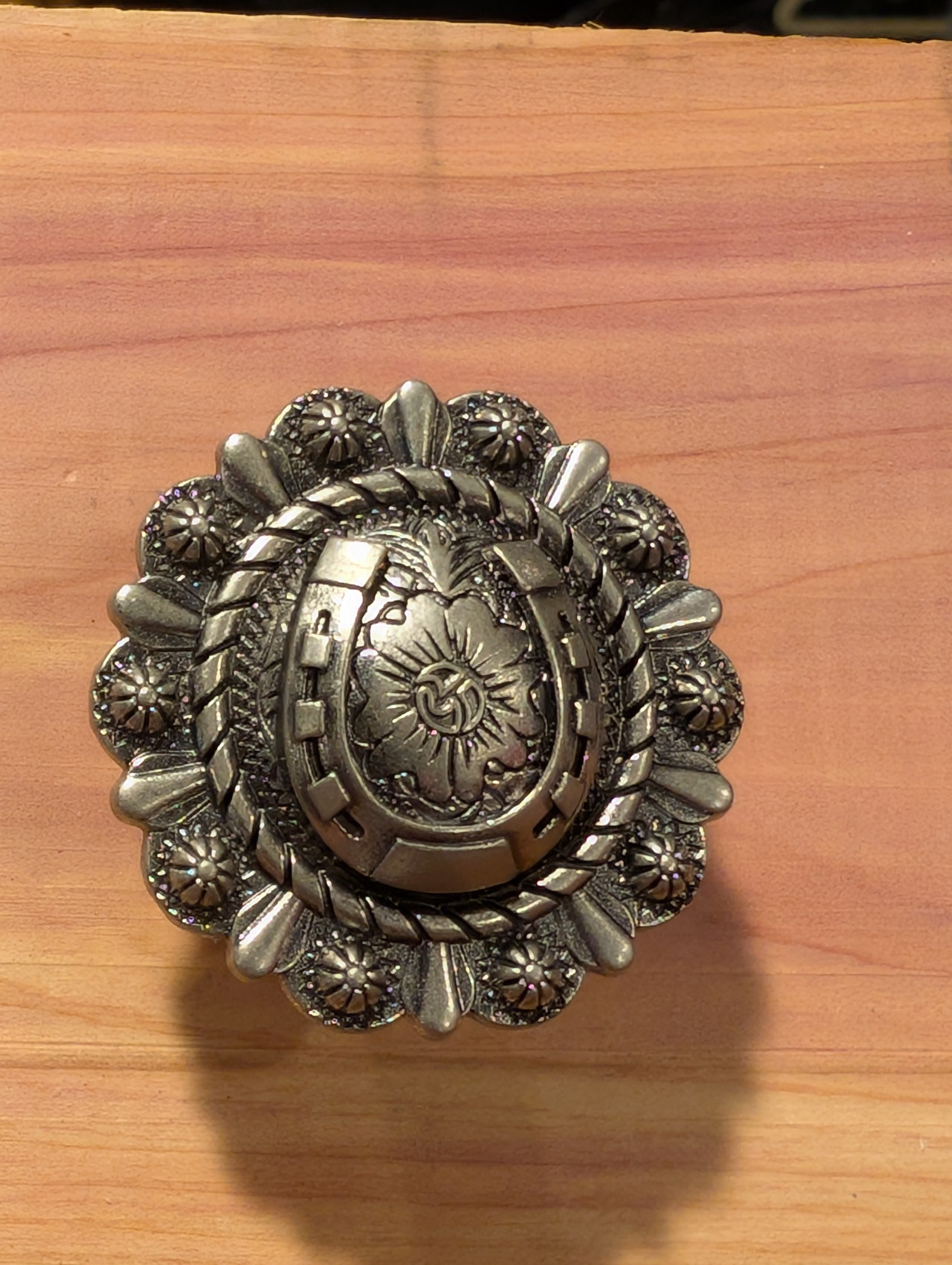 Western-style cabinet knobs featuring antique finishes and unique western patterns on wood table.