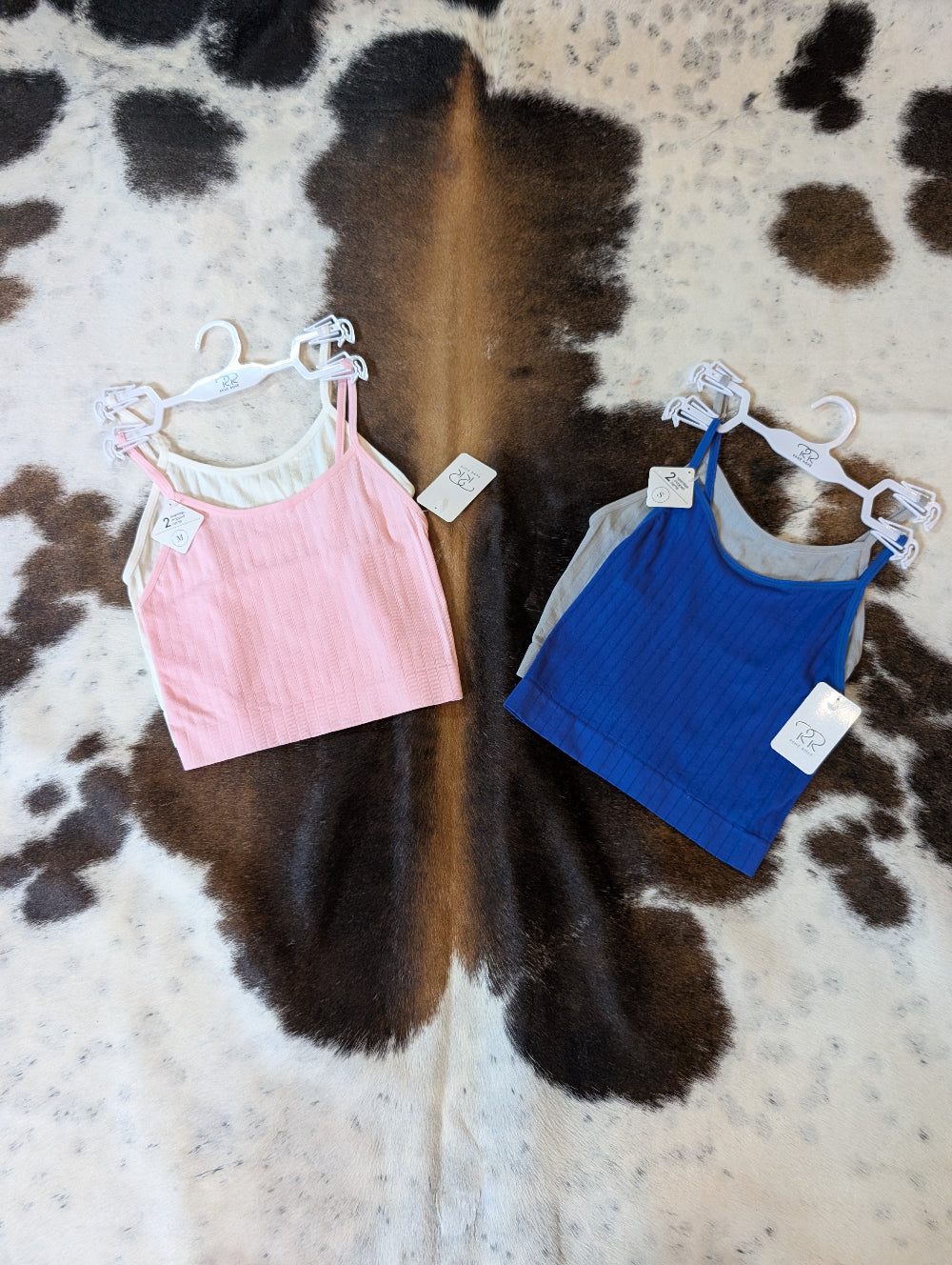 Seamless cropped camis in a two-pack, displayed in neutral colors folded neatly on cowhide rug
