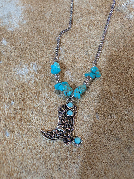 Necklace with boot pendant and turquoise stones on a wooden surface