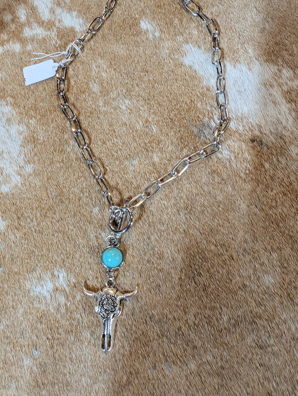 Necklace with bull head and turquoise stone pendant on a textured brown surface