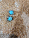 Pair of earrings with turquoise stones on a brown fur background