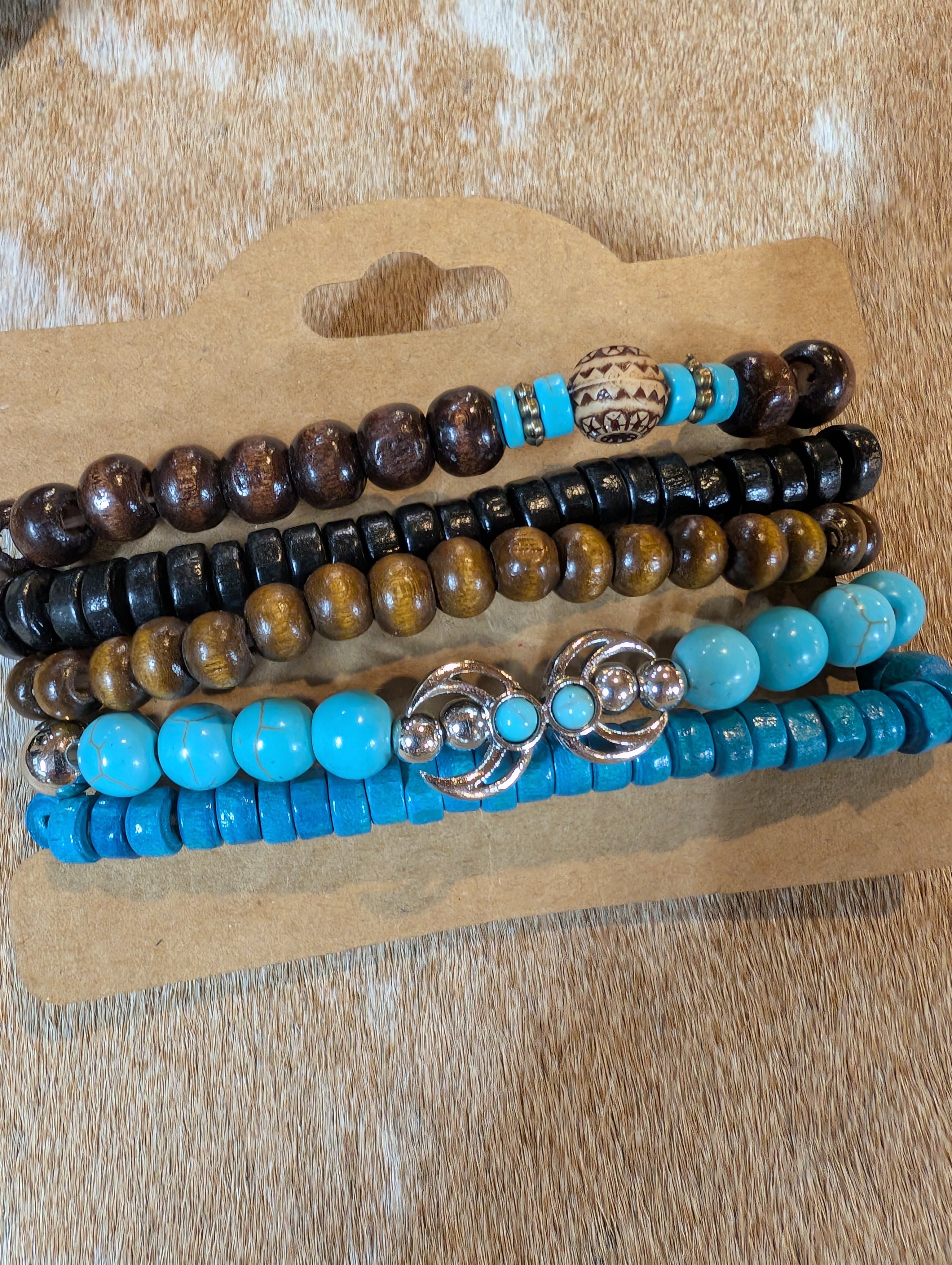 Set of five beaded bracelets with turquoise and brown beads on a cardboard holder.