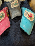 Three colorful caps with 'Farm Girl' and tractor designs on a dark textured surface.