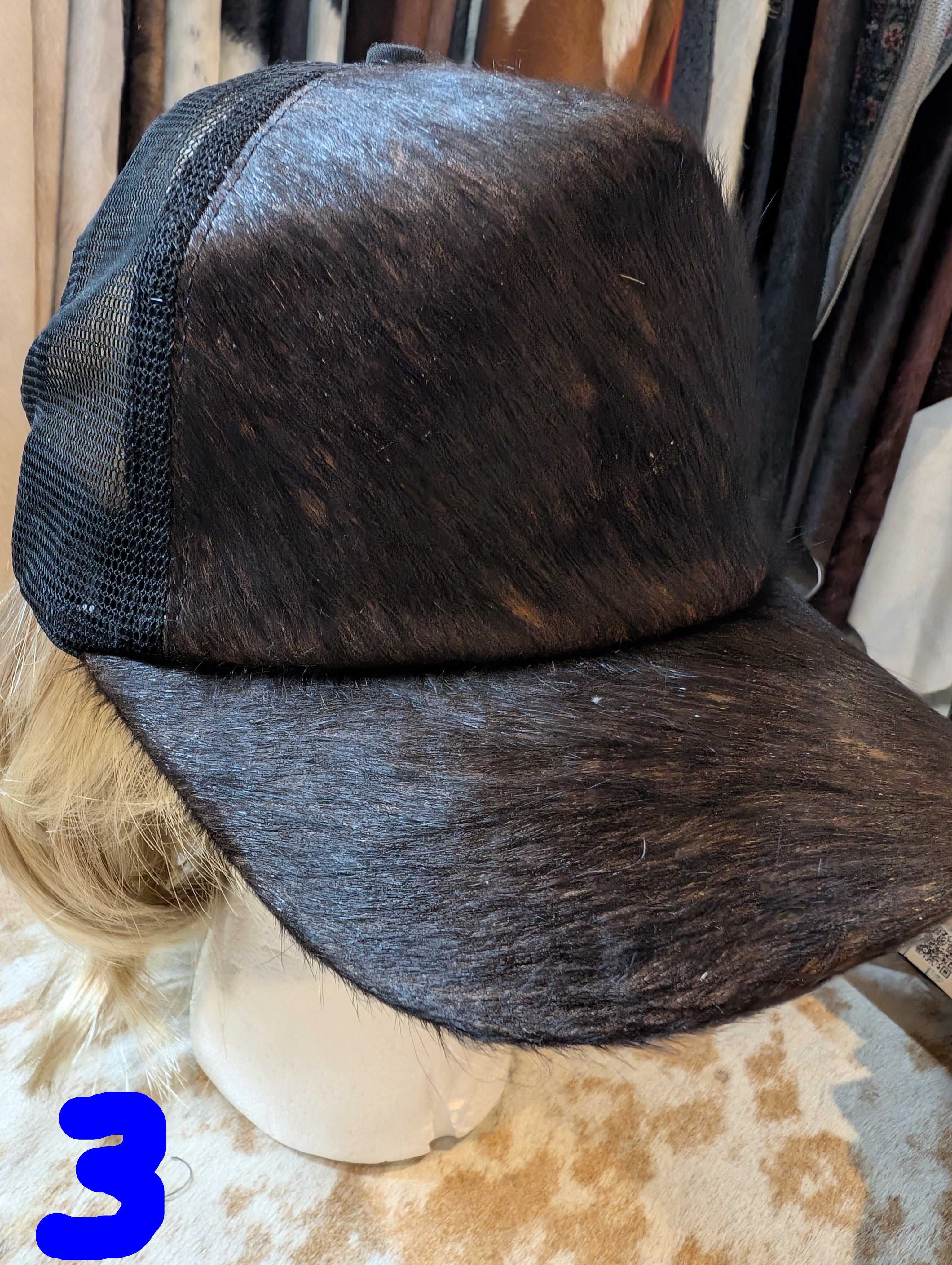 Black cowhide leather cap on a mannequin head with a textured background