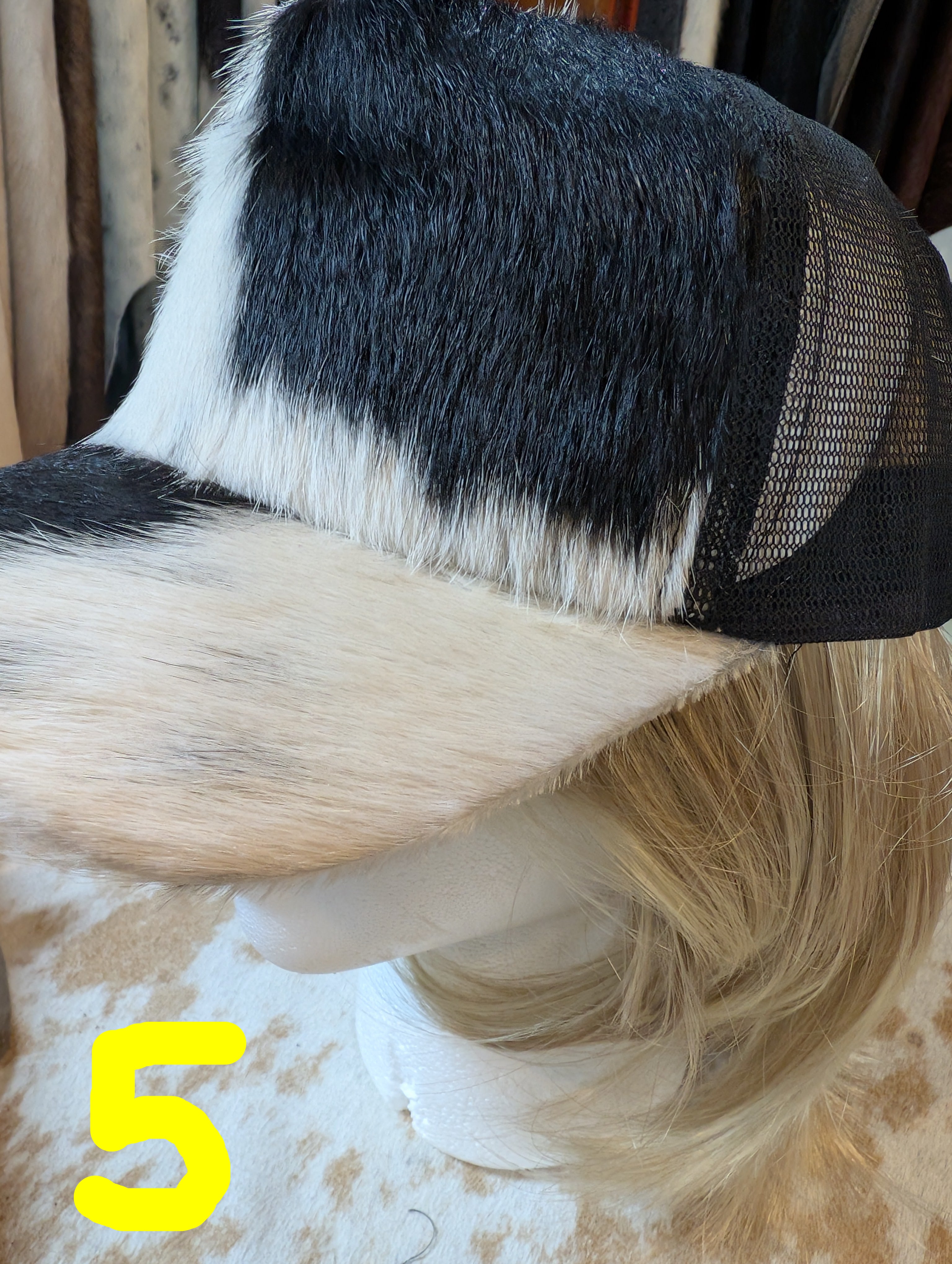 Mannequin head with black and white hair and a mesh cap on a neutral background