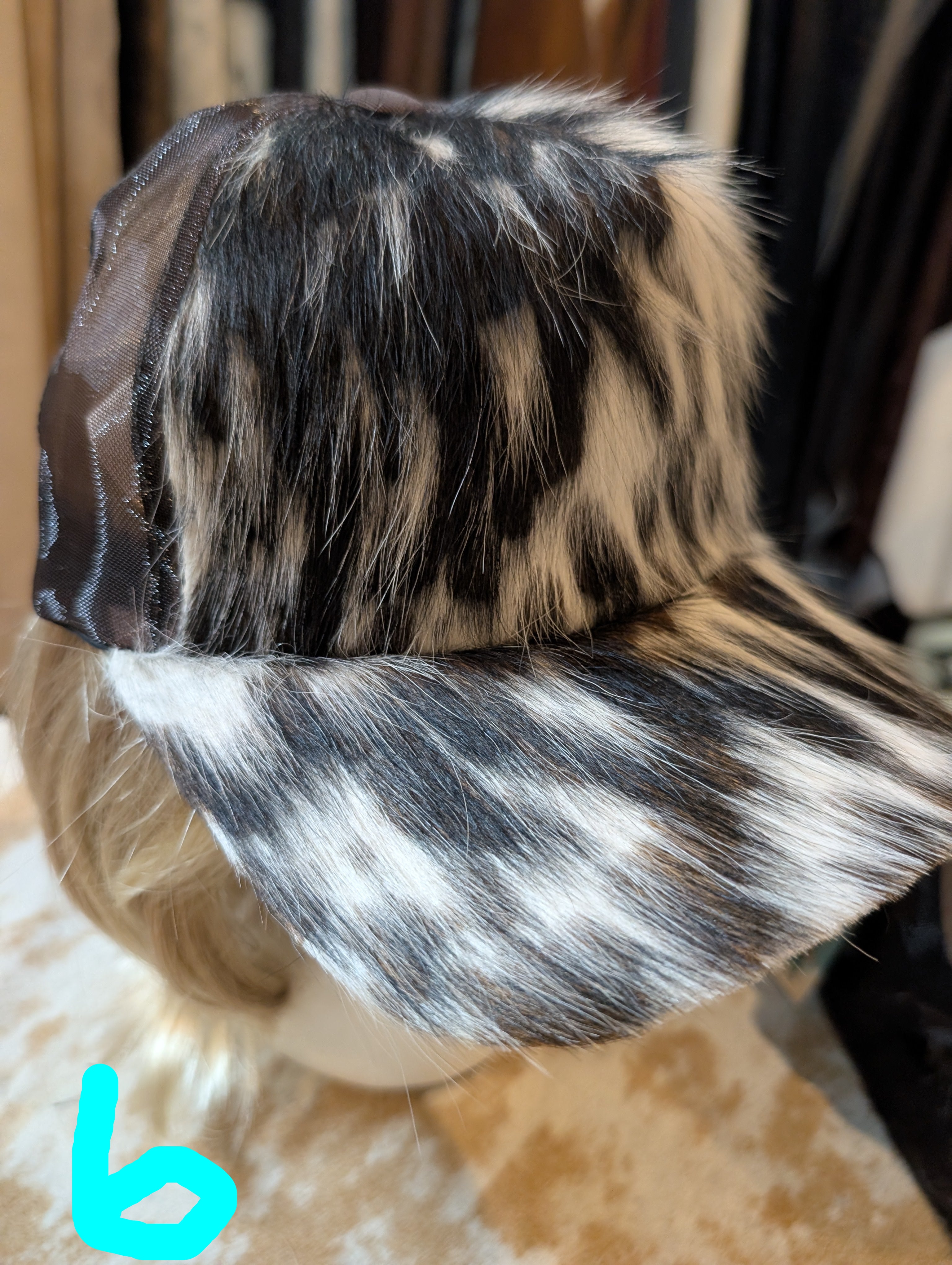 Partial view of a wig with black, brown, and white hair on a mannequin head.