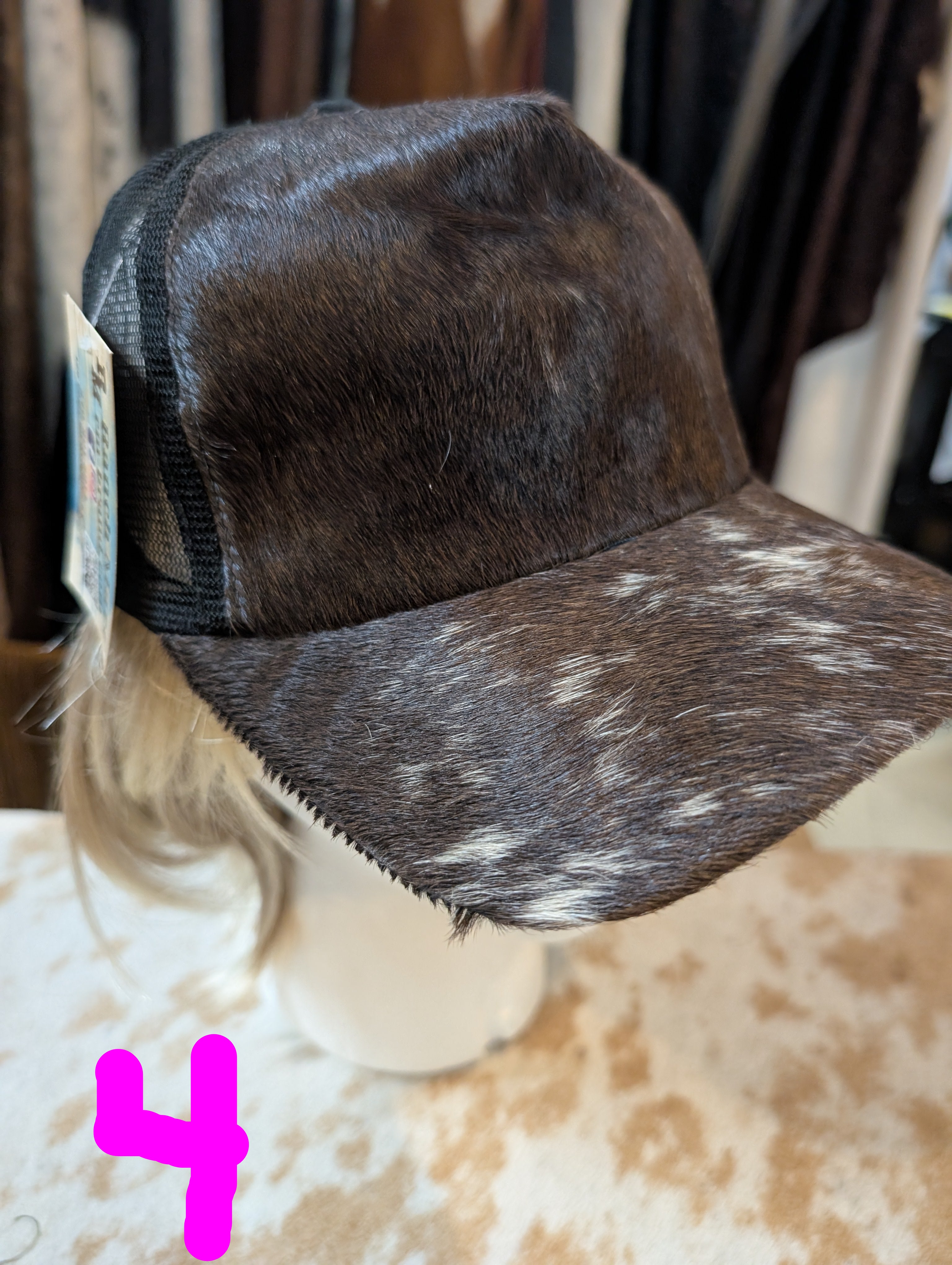 Brown and white cowhide cap on a mannequin head with a blurred background