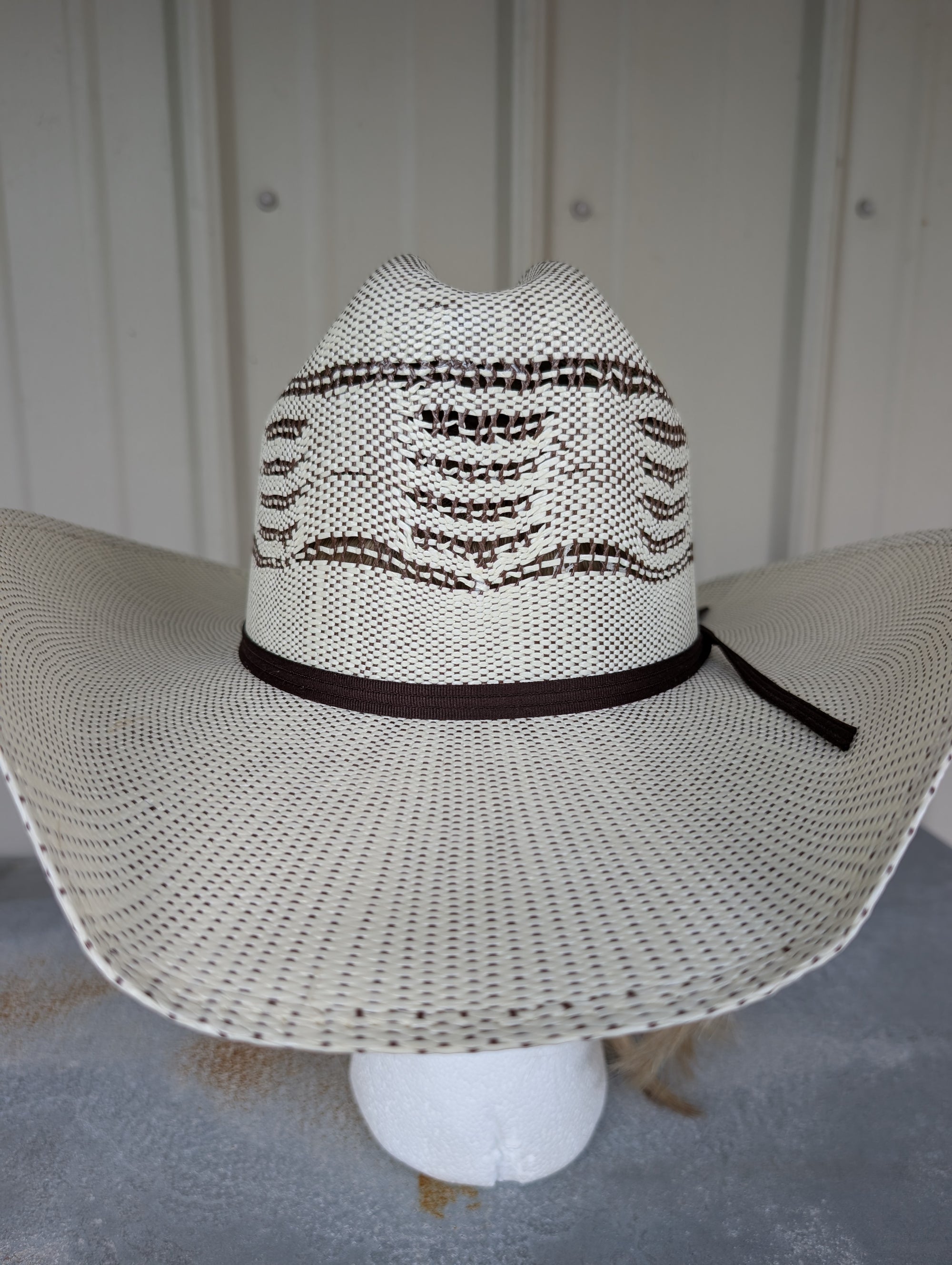 White straw hat with black band on a neutral background