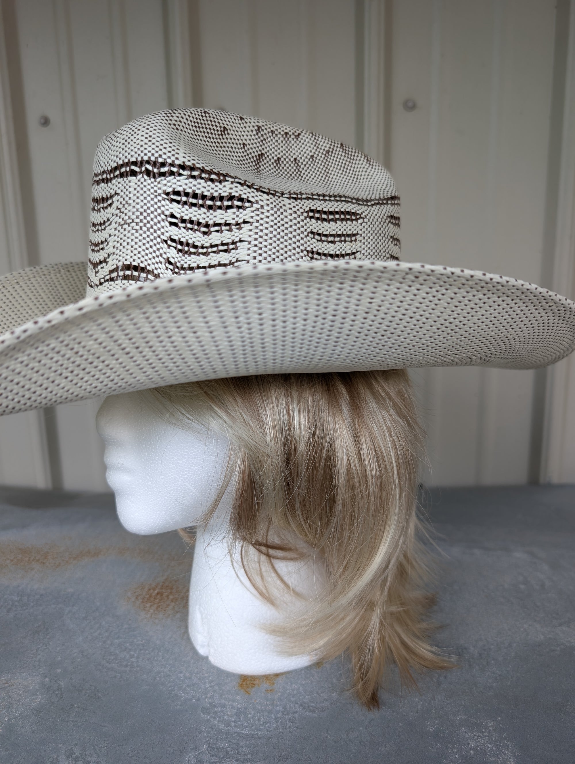 Mannequin head with a white straw hat on a neutral background