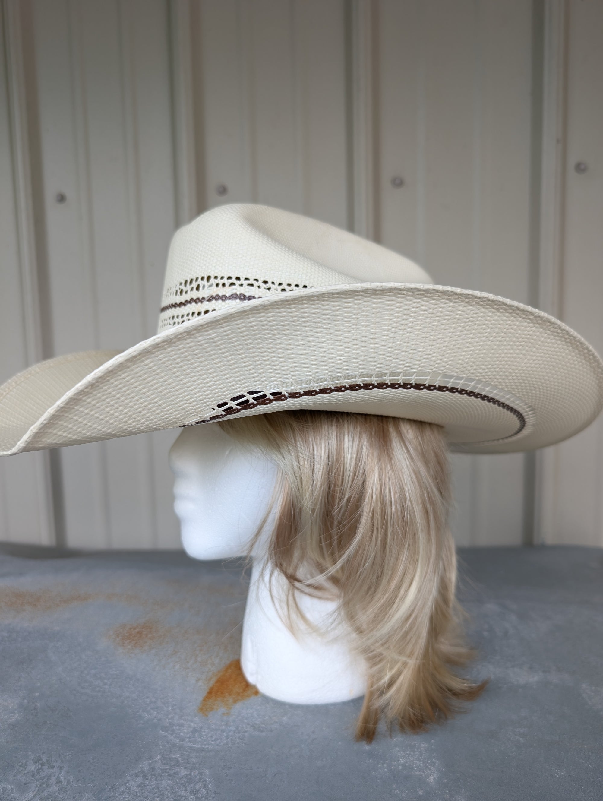 Beige cowboy hat on a mannequin head against a neutral background