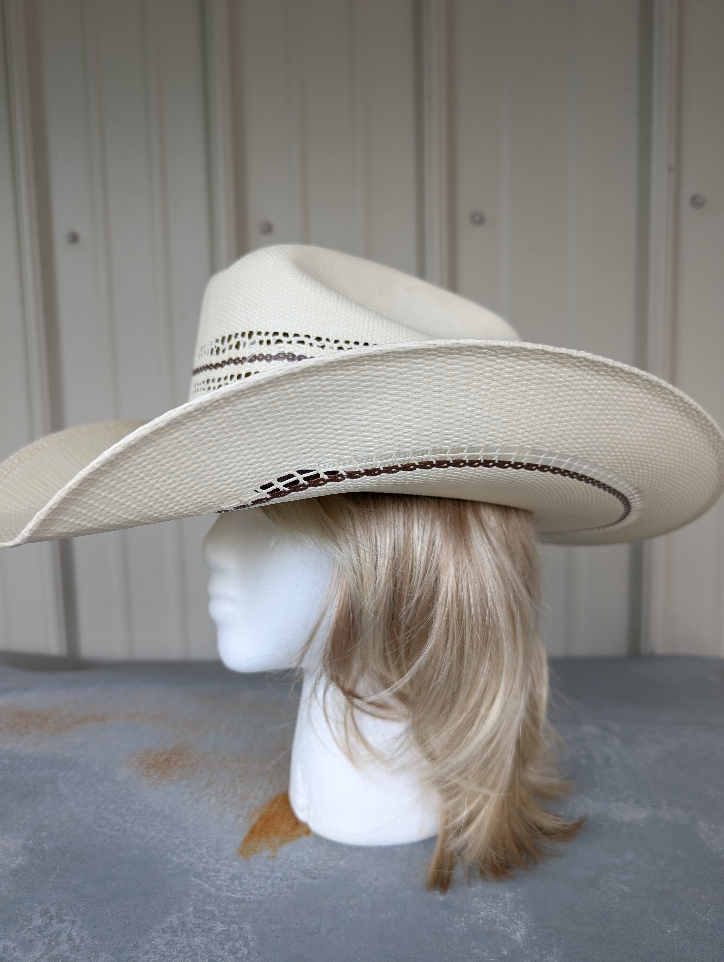 Beige cowboy hat on a mannequin head against a neutral background