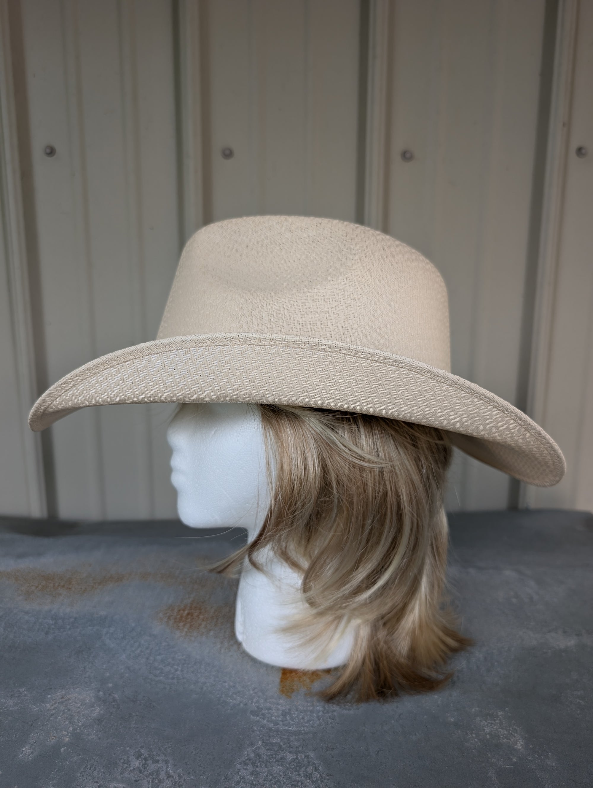 Beige wide-brimmed hat on a mannequin head against a neutral background