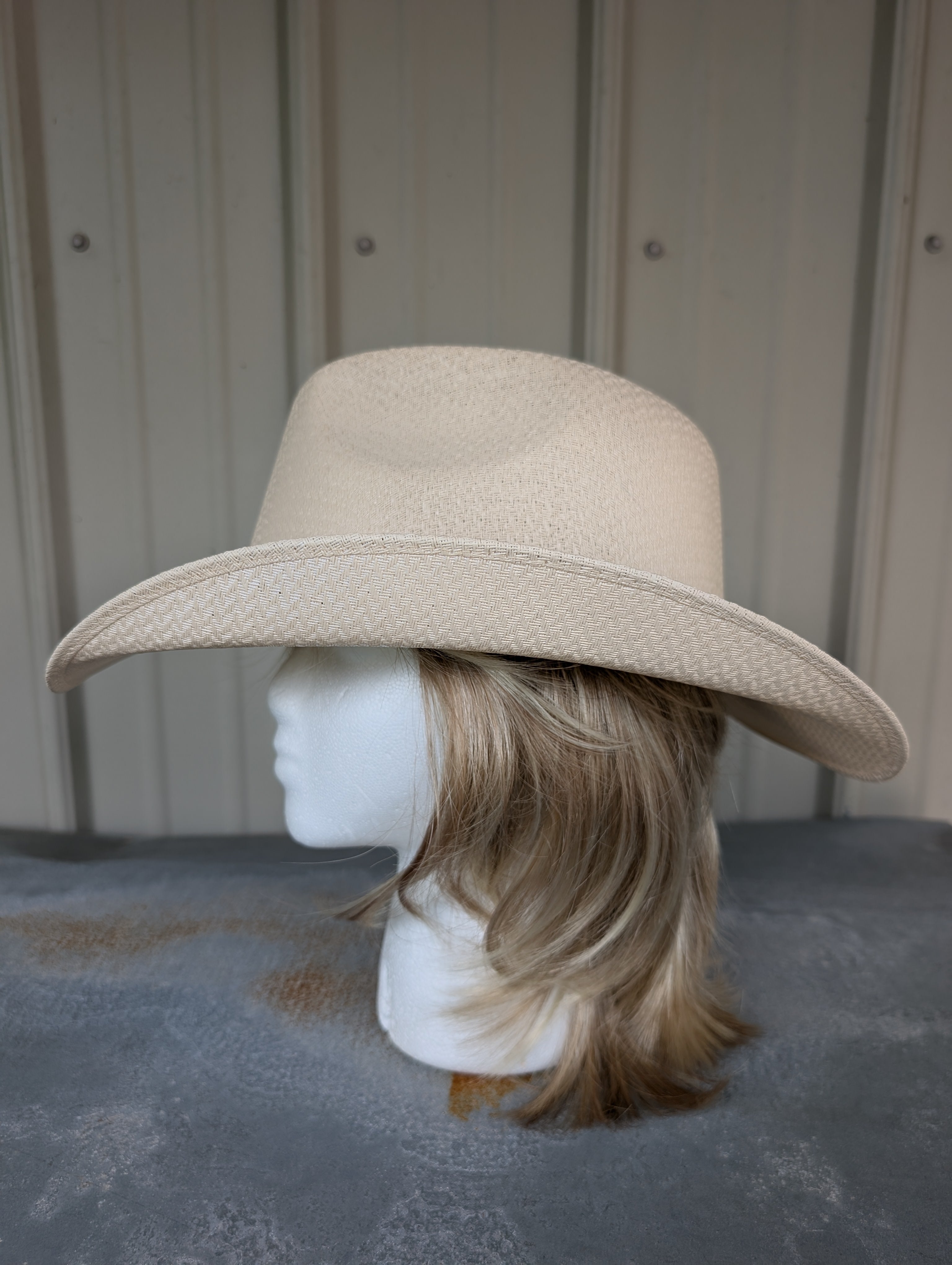 Beige wide-brimmed hat on a mannequin head against a neutral background