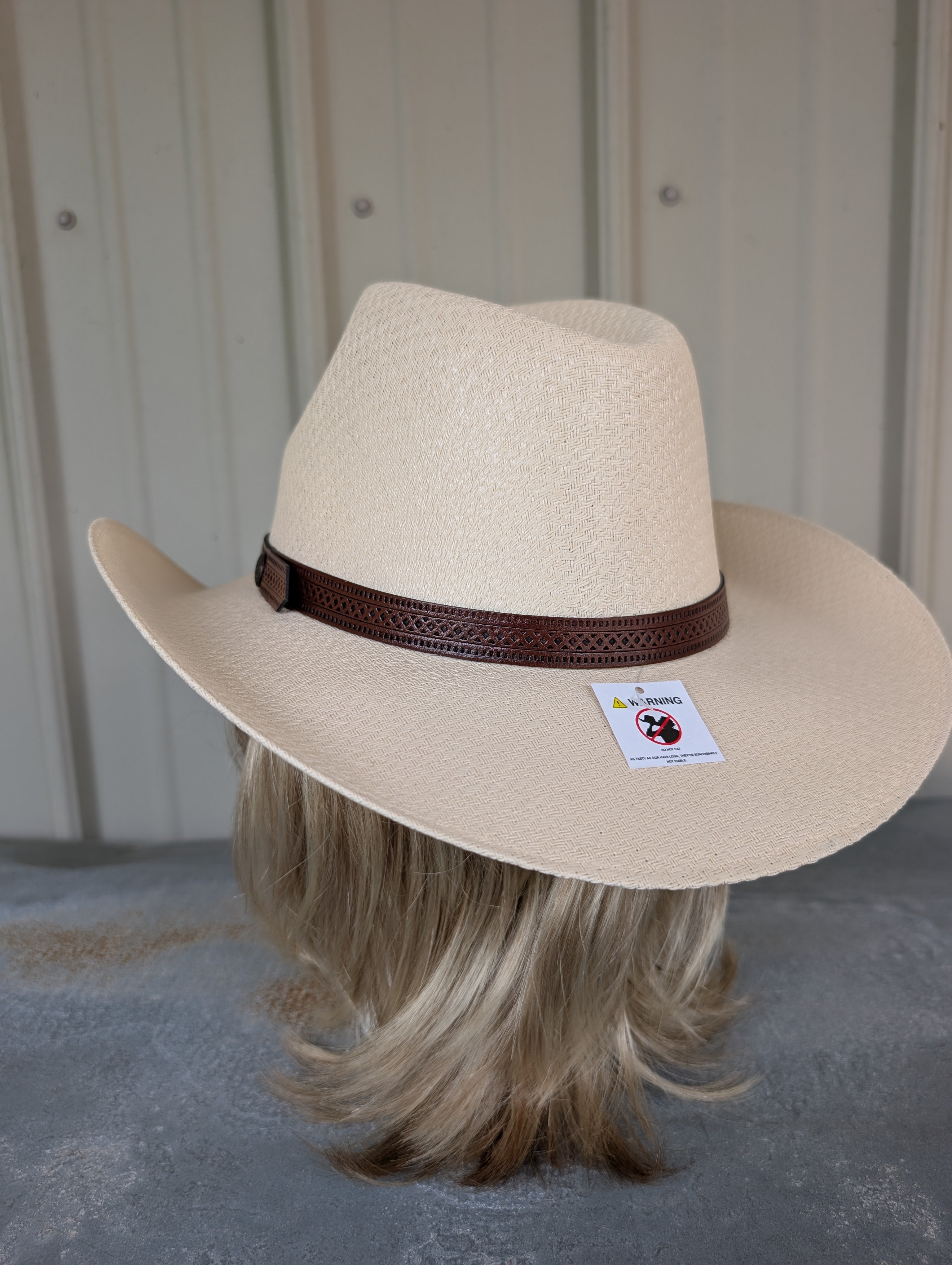 Beige cowboy hat with a brown band on a mannequin head against a neutral background