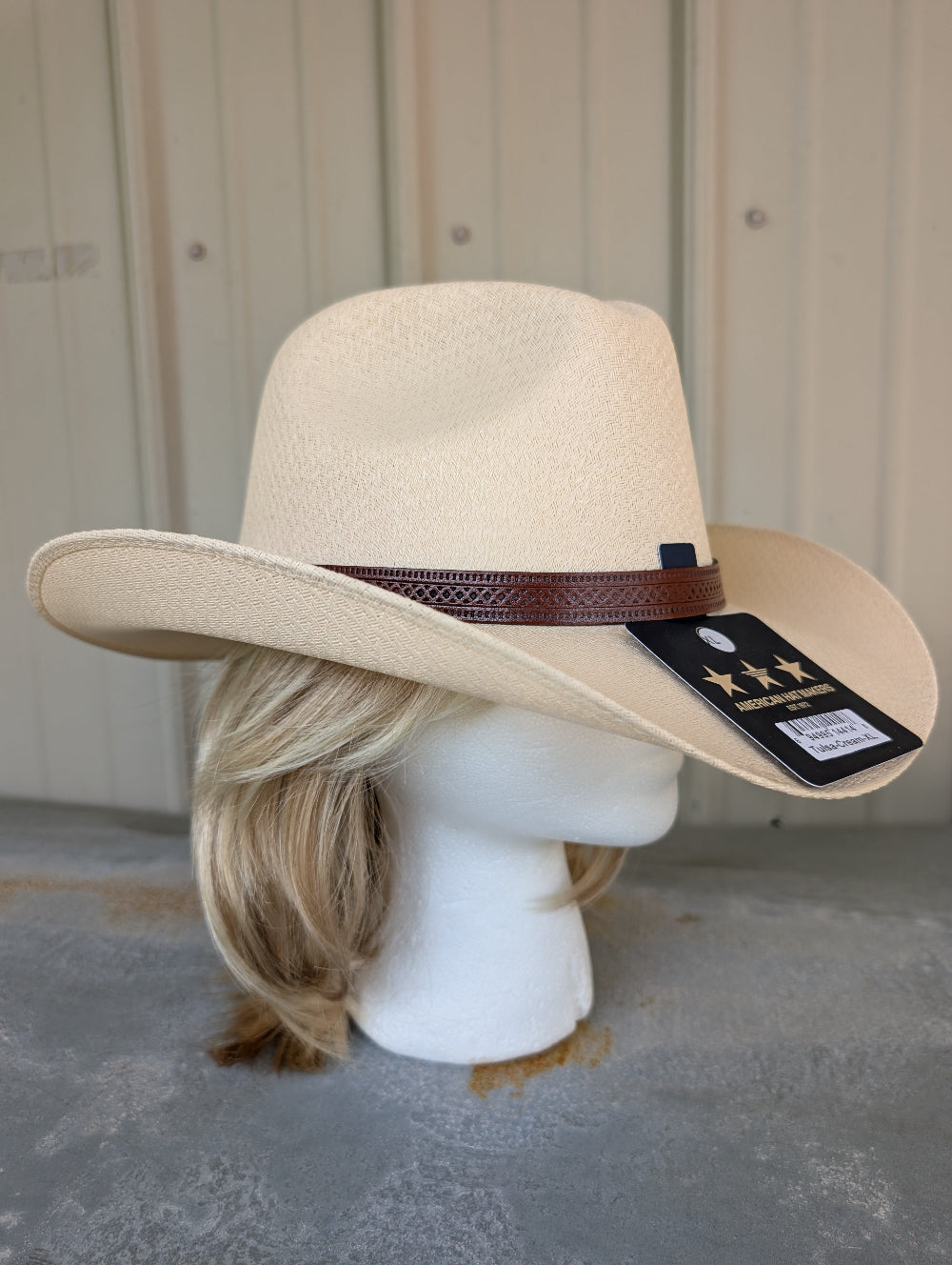 Beige cowboy hat on a mannequin head with a visible brand tag against a neutral background