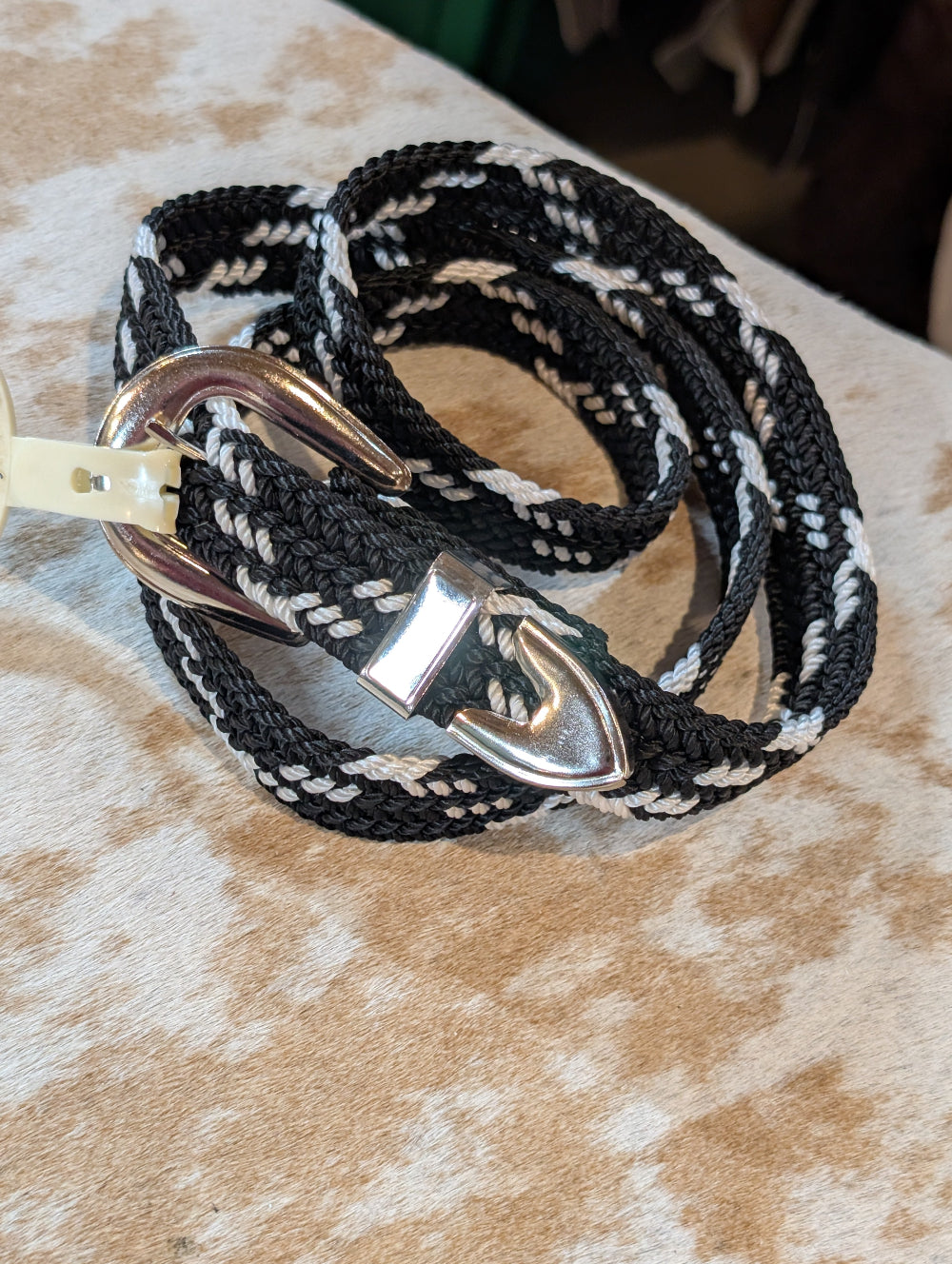 Black and white braided leash with a metal anchor clip on a textured surface