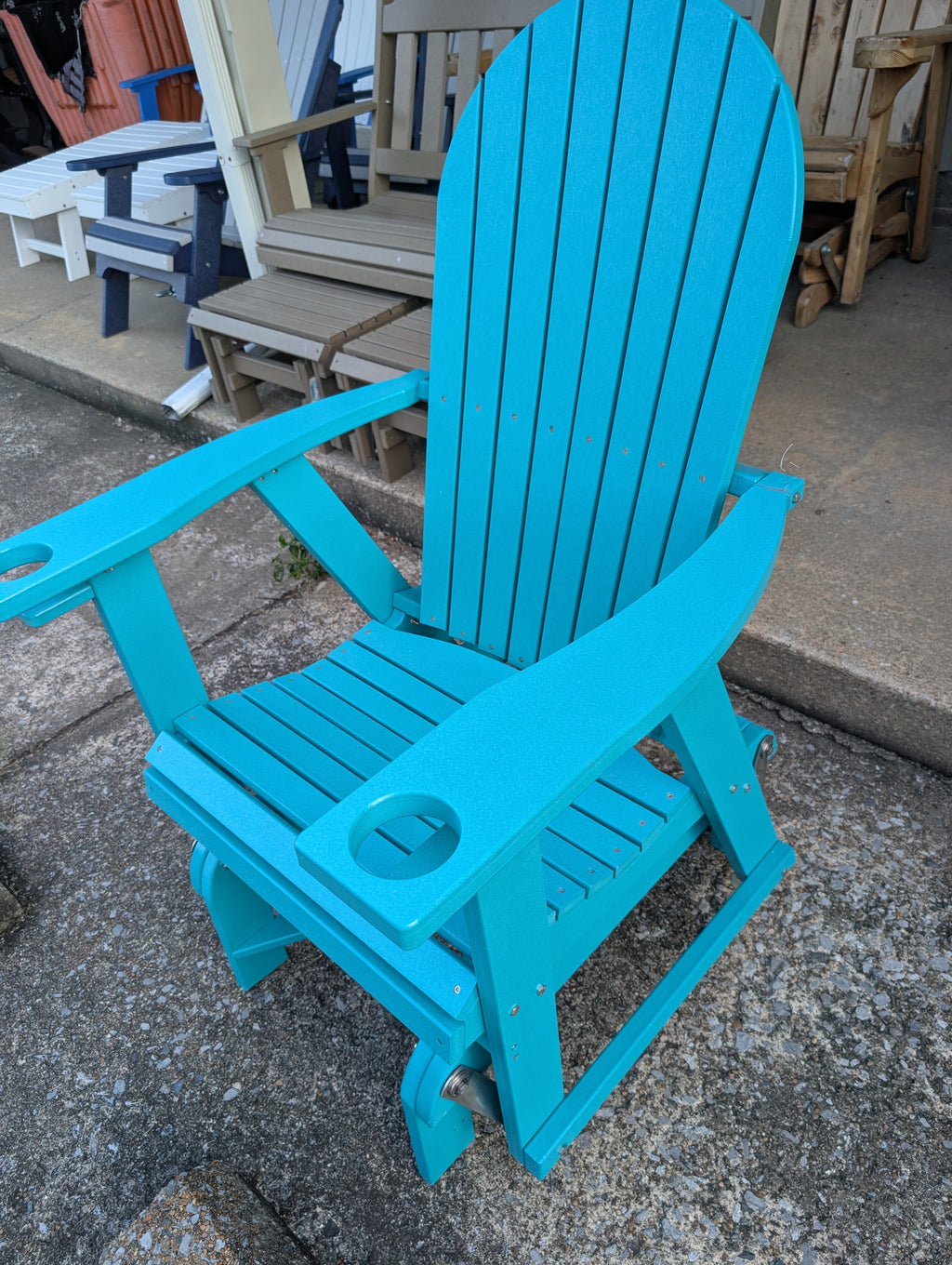 Blue glider chair on a concrete surface with outdoor furniture in the background.