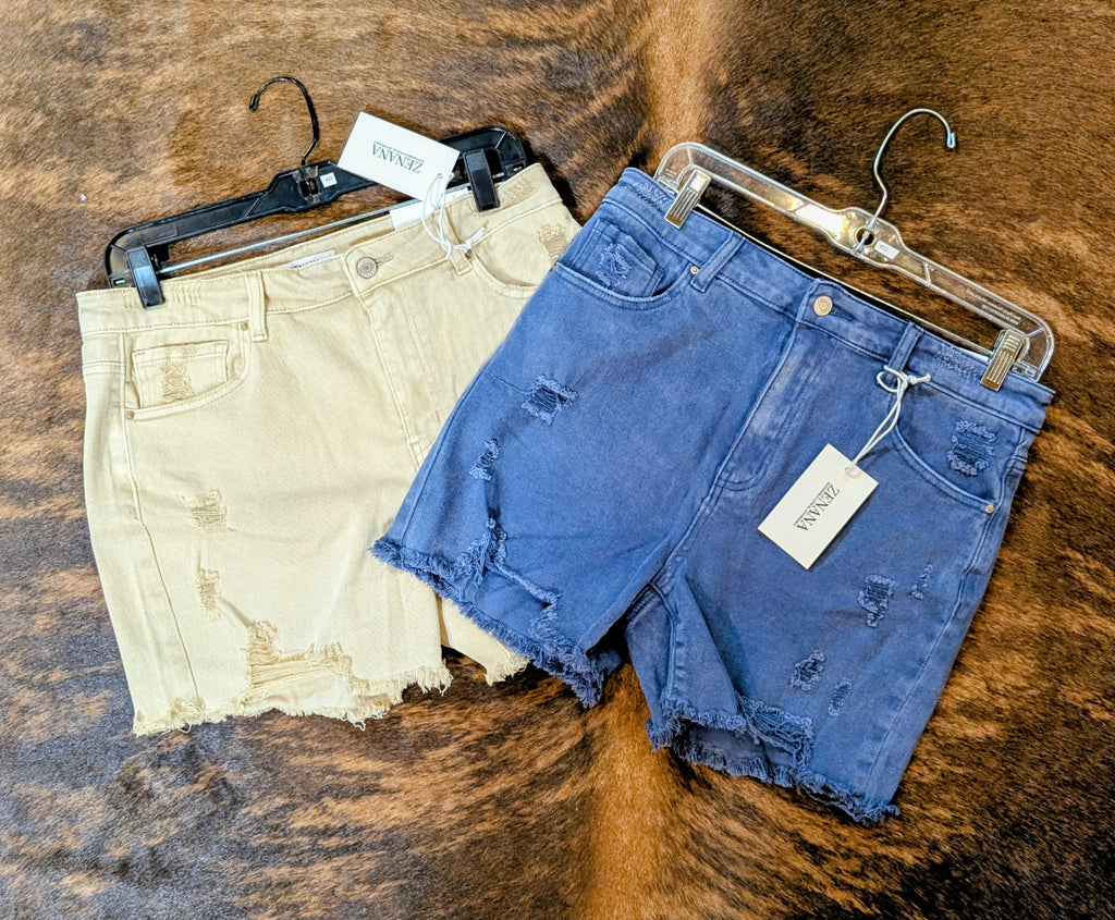 Two pairs of shorts on hangers against a textured brown background