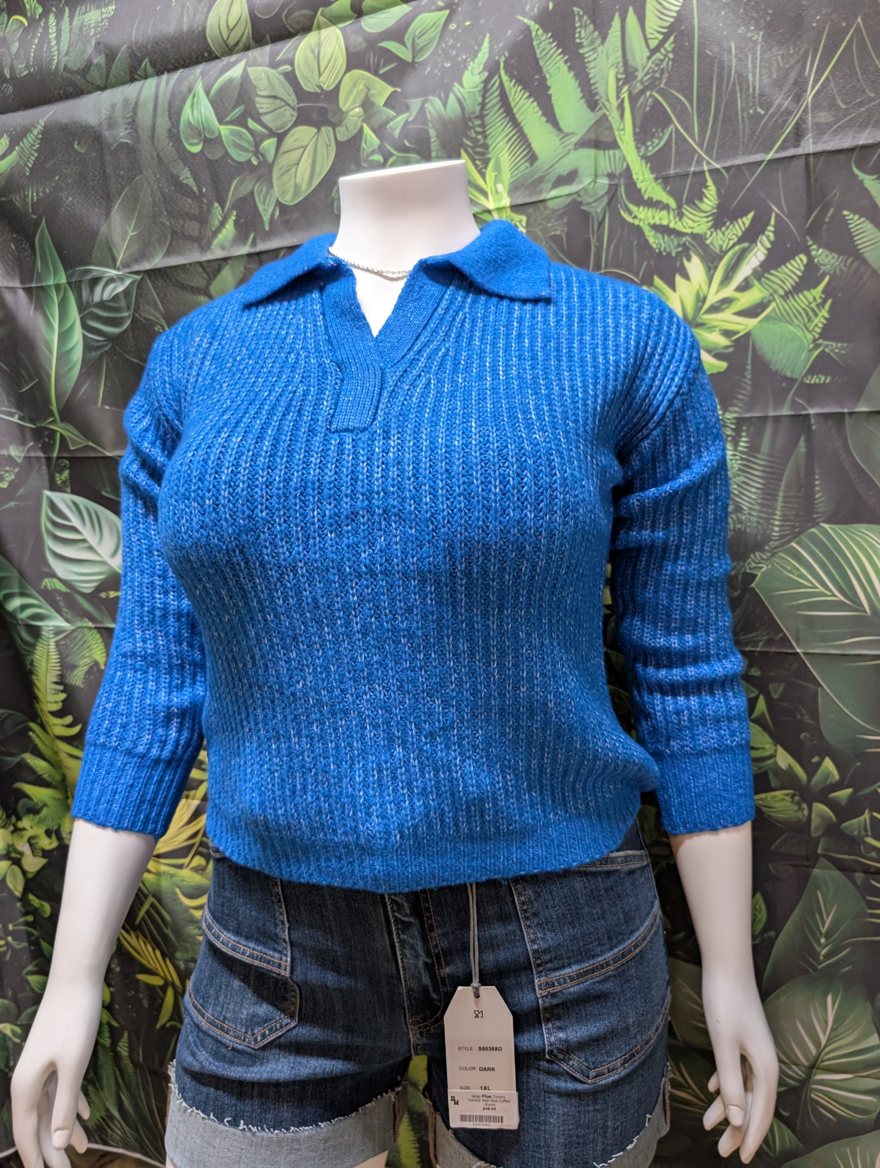 Blue sweater on a mannequin with a leafy patterned background