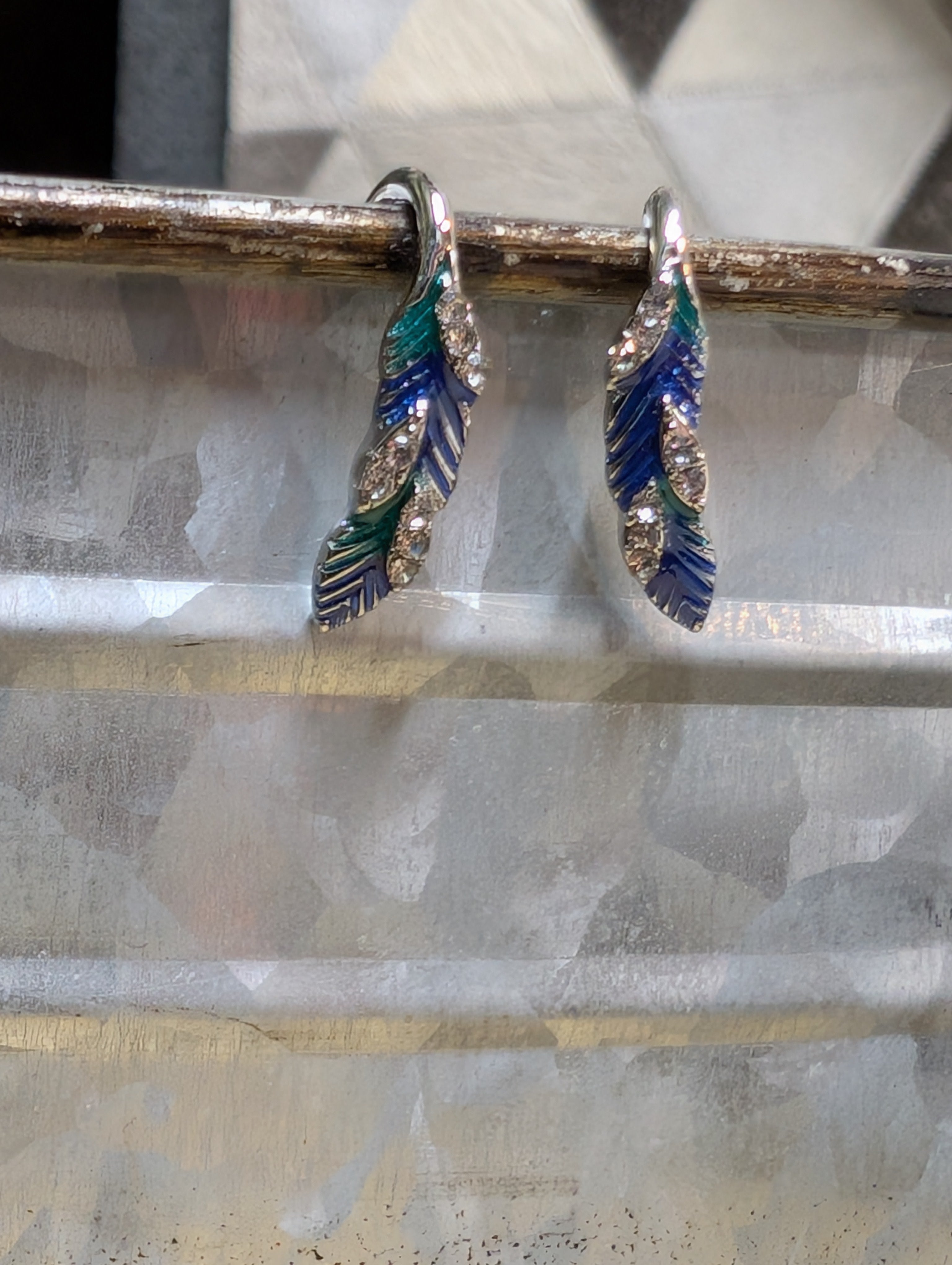 Silver feather drop earrings with blue enamel and crystal detailing for western style.
