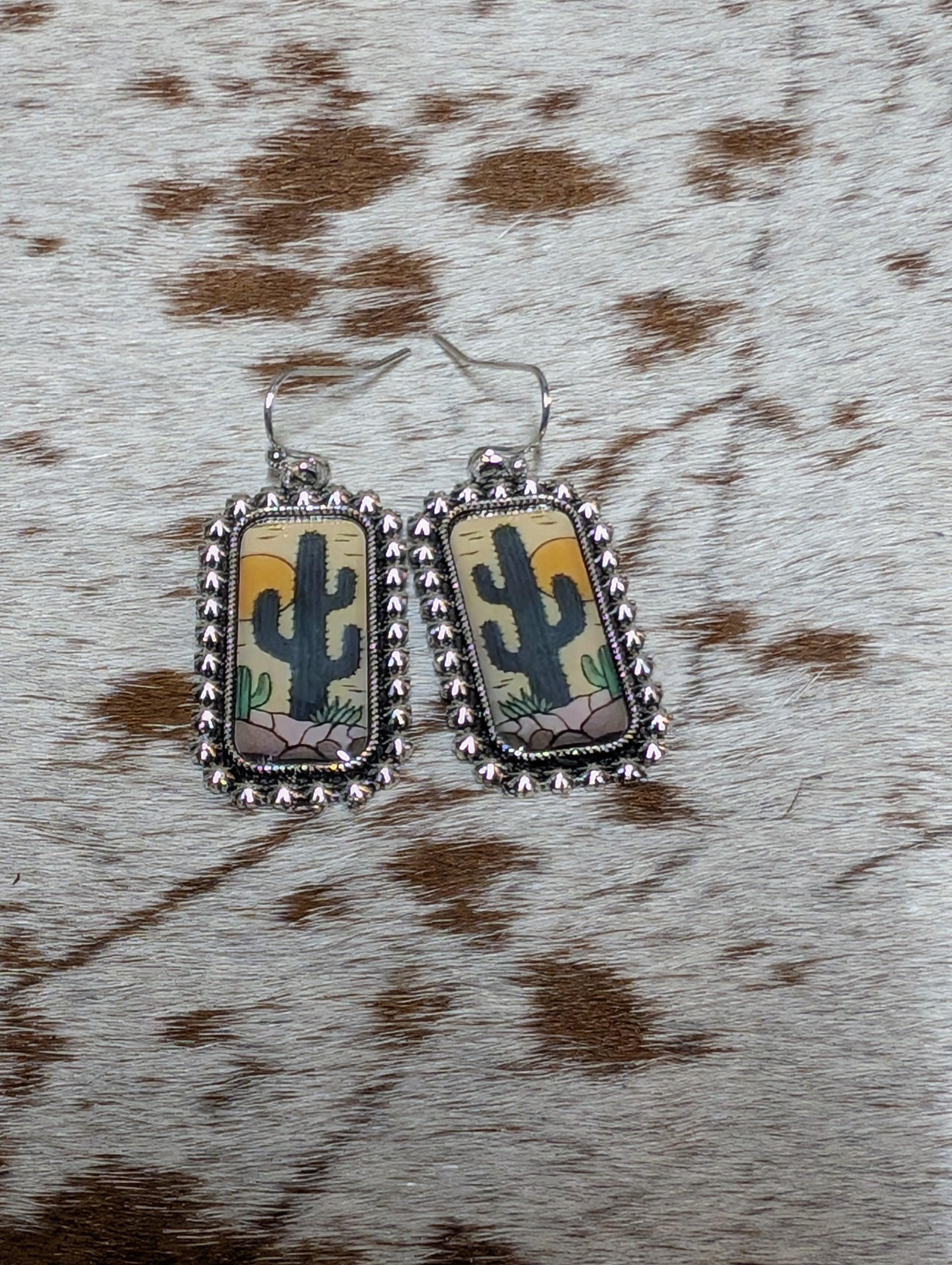 Rectangular earrings with cactus design on a cowhide background