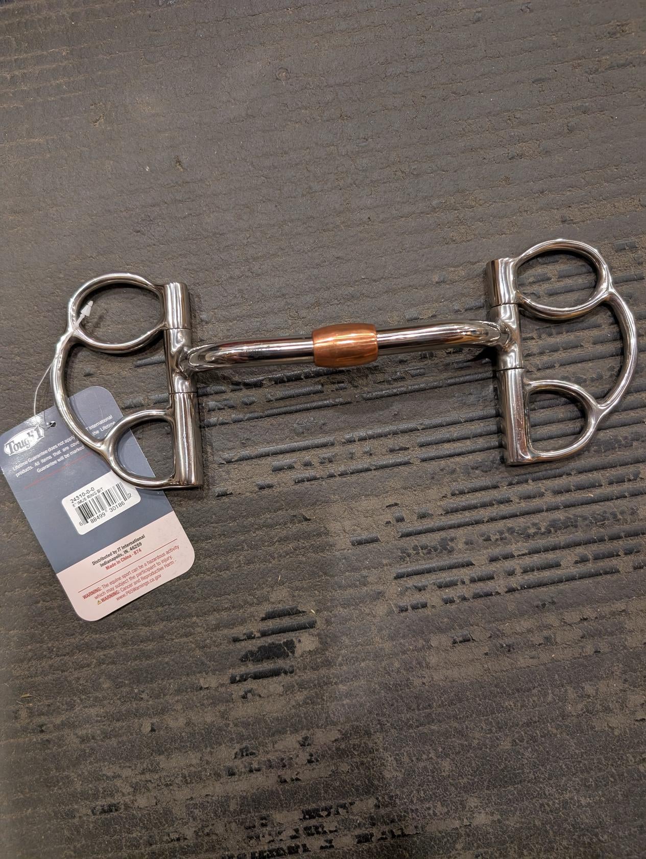 Metal horse bridle bit on a textured surface with a visible brand tag.