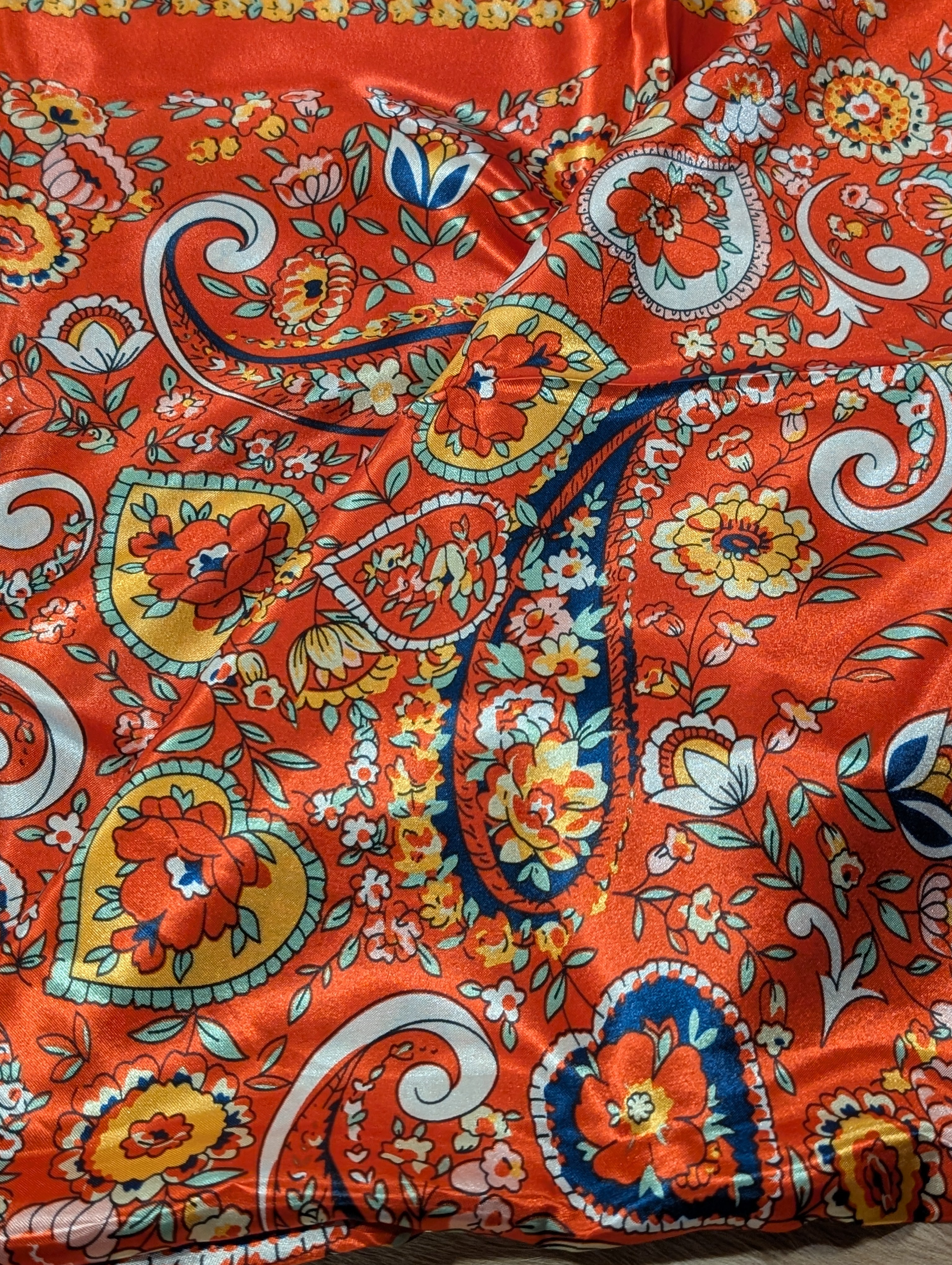 Close-up of a vibrant orange fabric with floral and paisley patterns