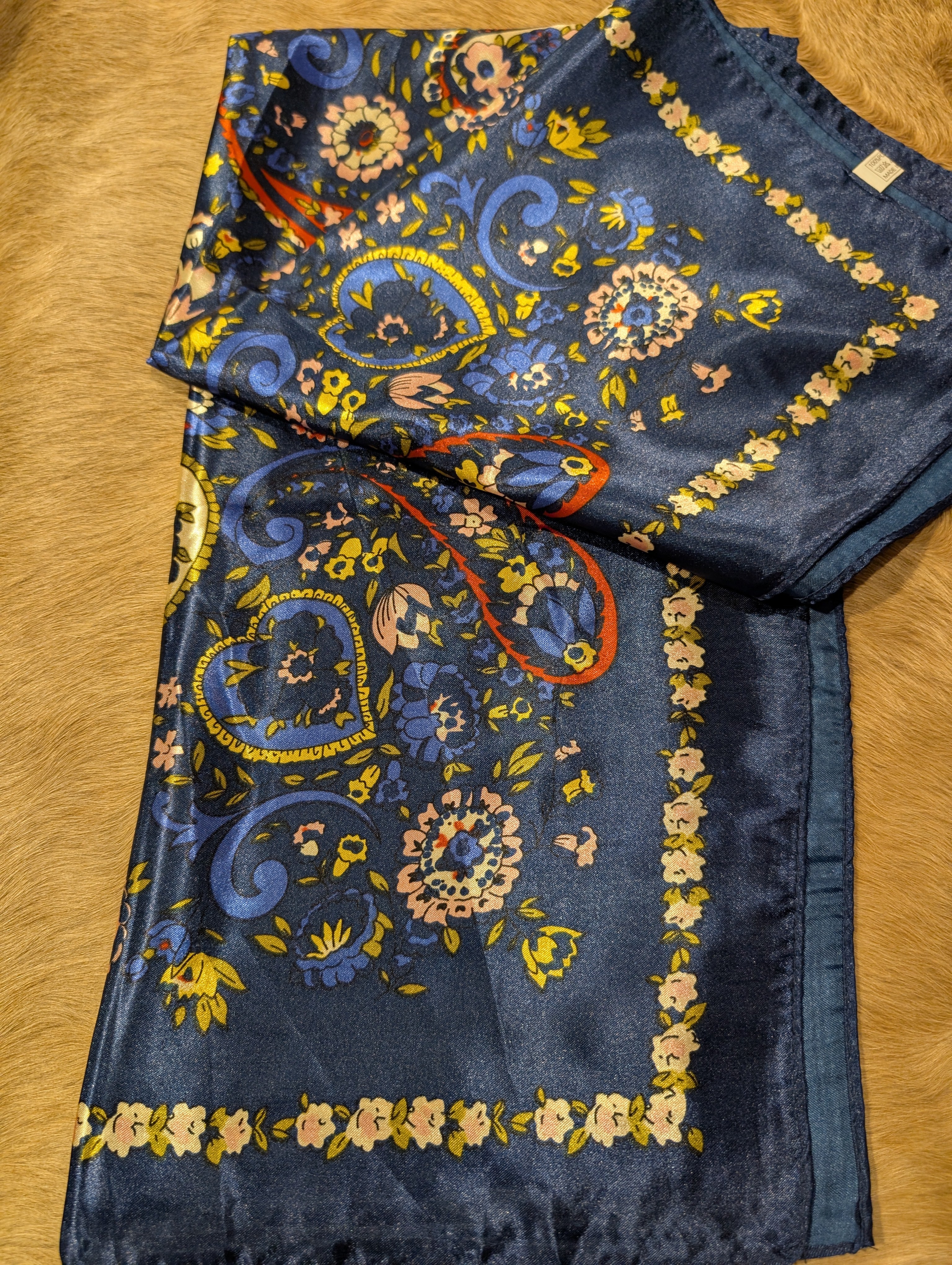 Decorative scarf with floral and paisley patterns on a wooden surface