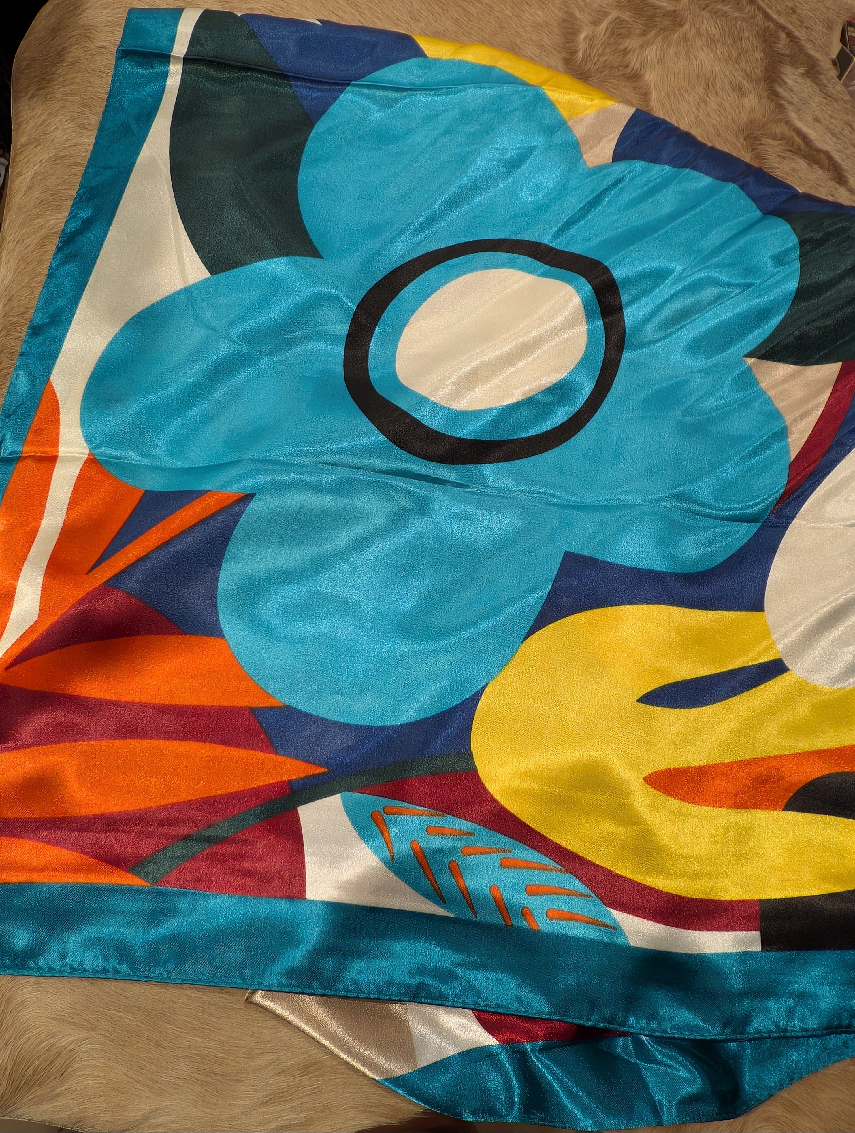 Colorful  scarf/wild rag  with a large blue flower design on a brown surface