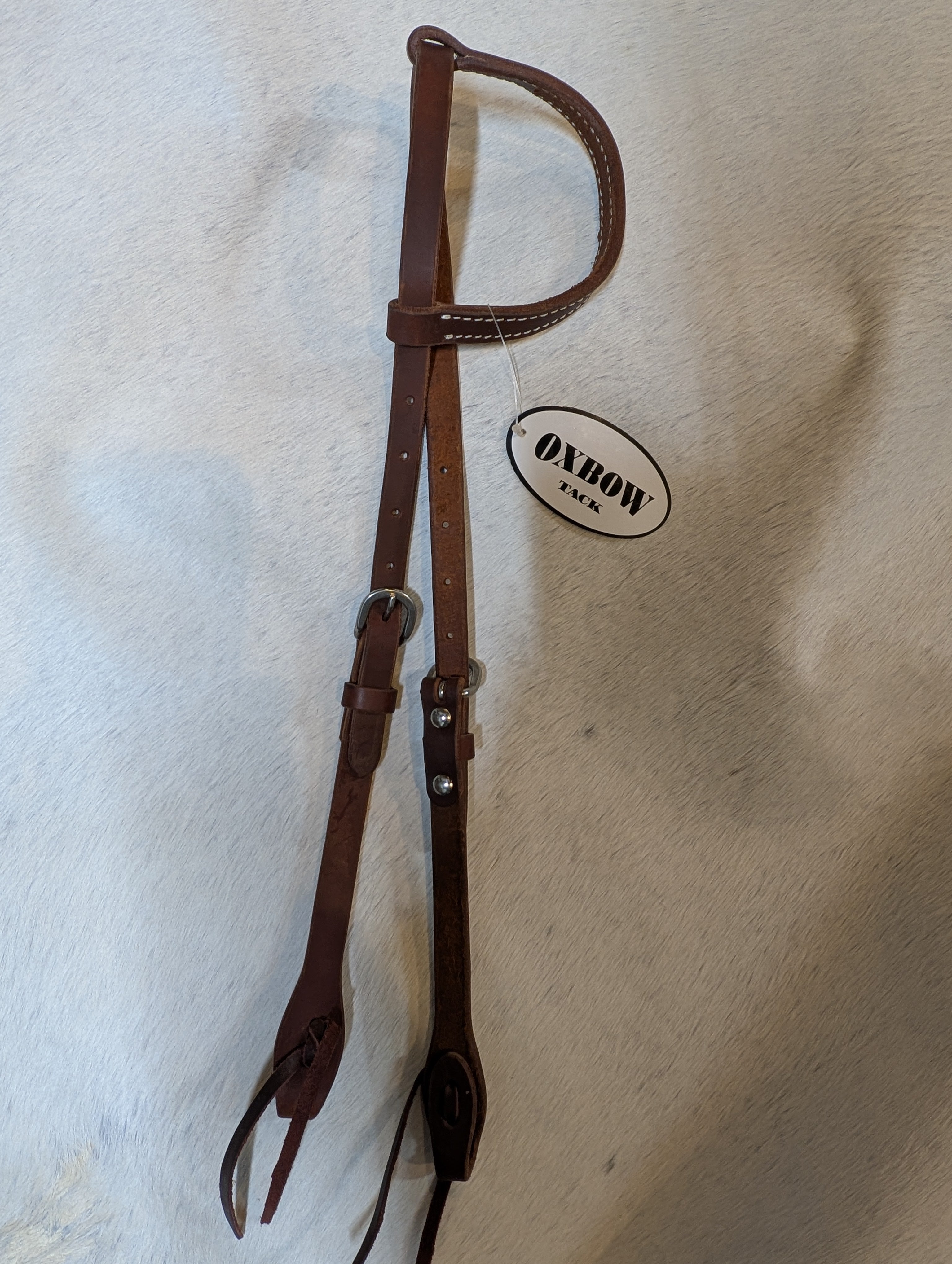 Brown leather bridle on a textured white surface with 'Oxbow' branding.