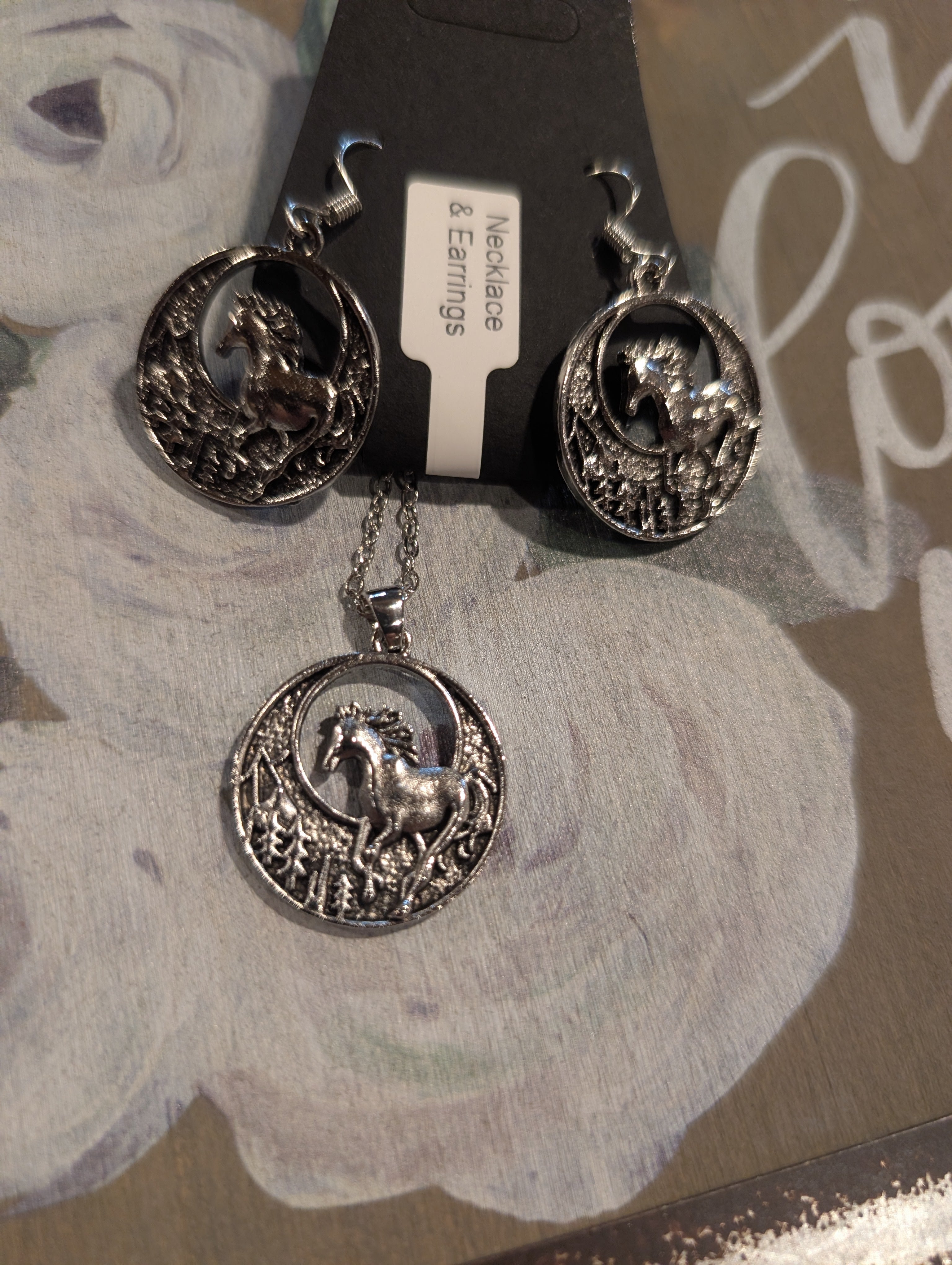 Silver horse-themed necklace and earrings on a floral card