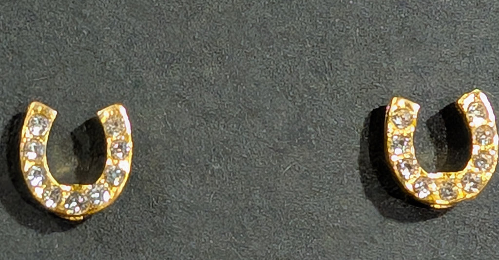 Gold horseshoe-shaped earrings with embedded stones on a dark background