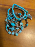 Turquoise beaded bracelet with silver crosses on a wooden surface