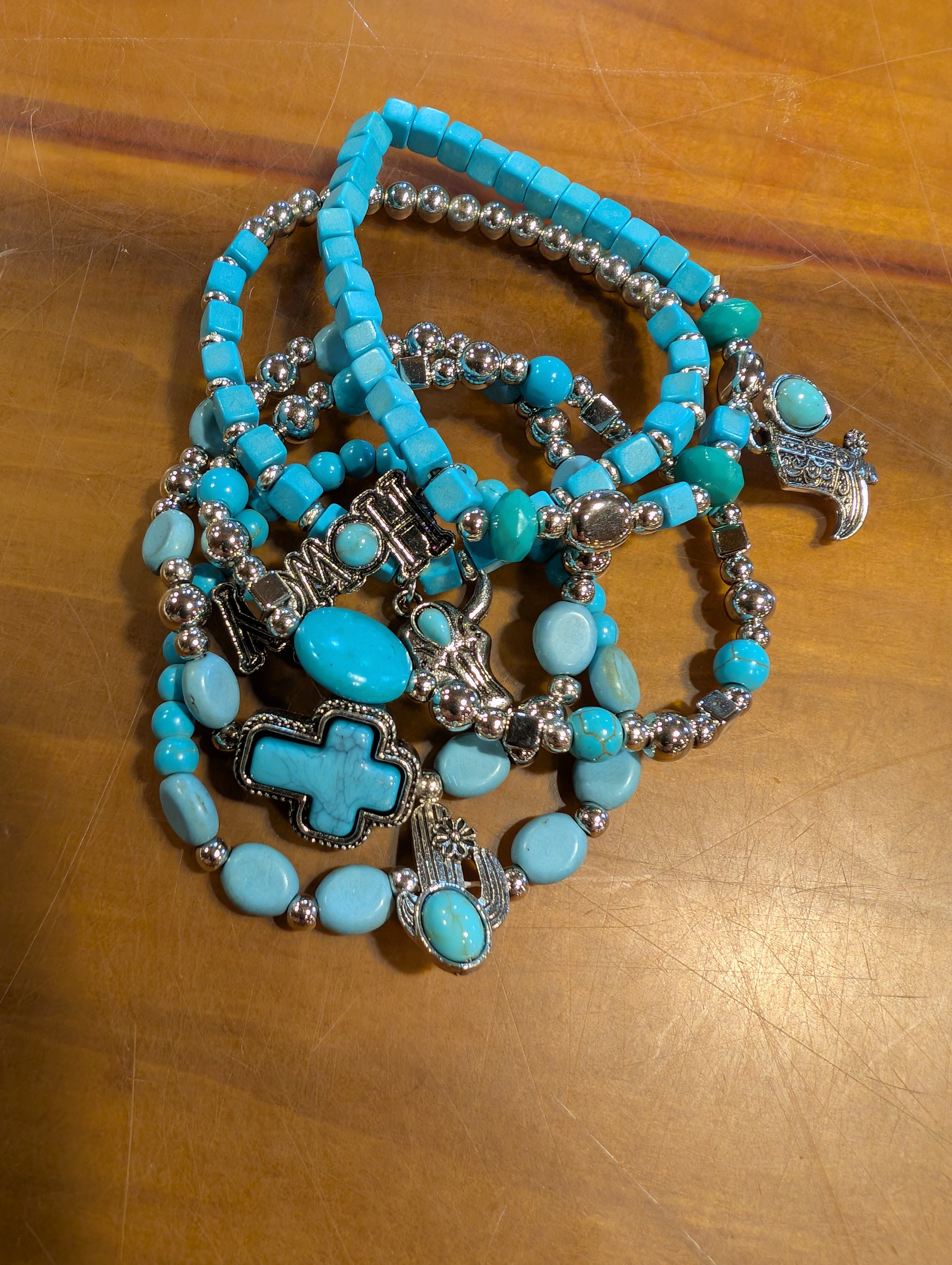 Turquoise beaded bracelet with silver crosses on a wooden surface