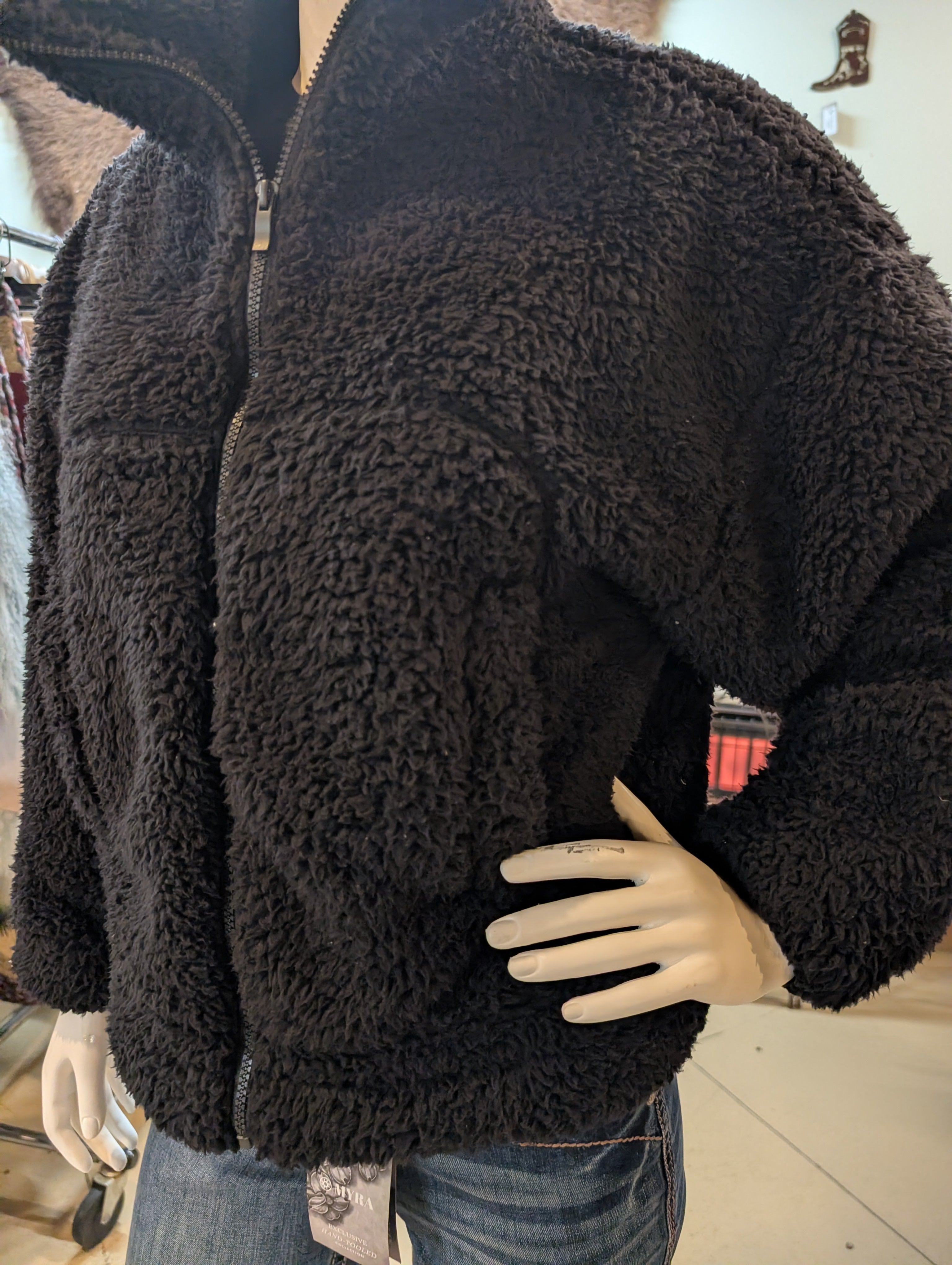 Black fleece jacket on a mannequin with a blurred indoor background