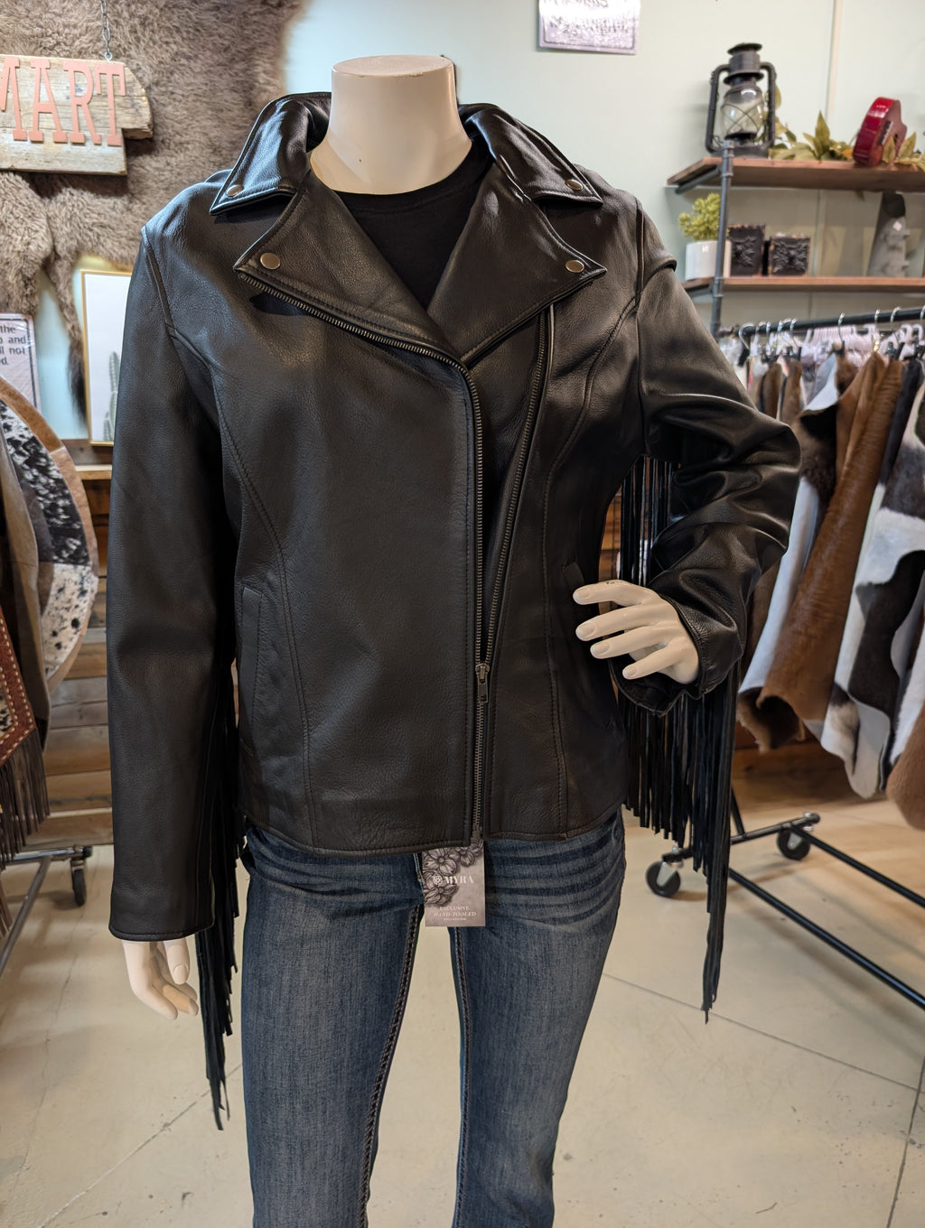 Black leather jacket with fringe on a mannequin in a store setting