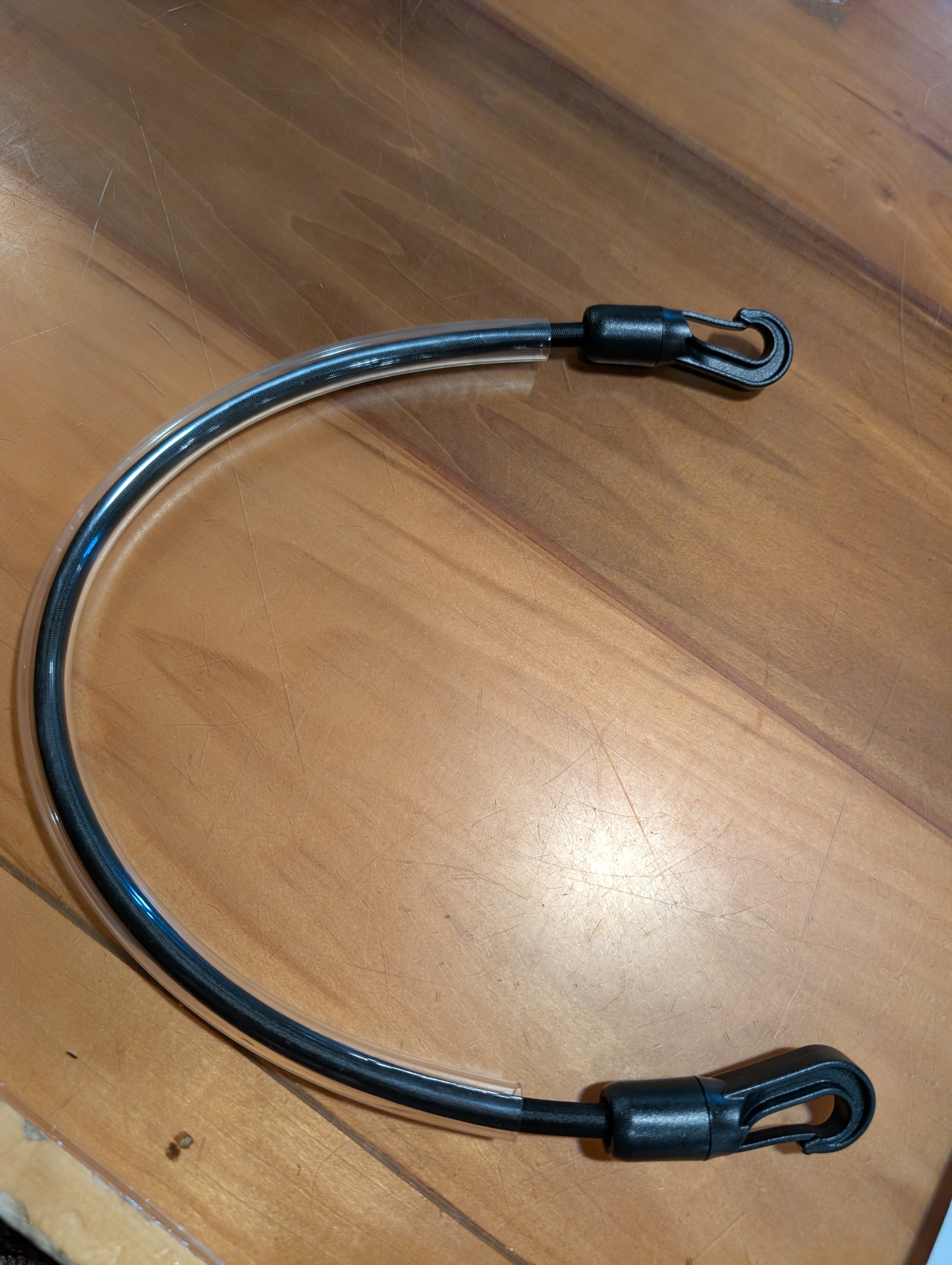 Black metal cable with a hook on a wooden surface