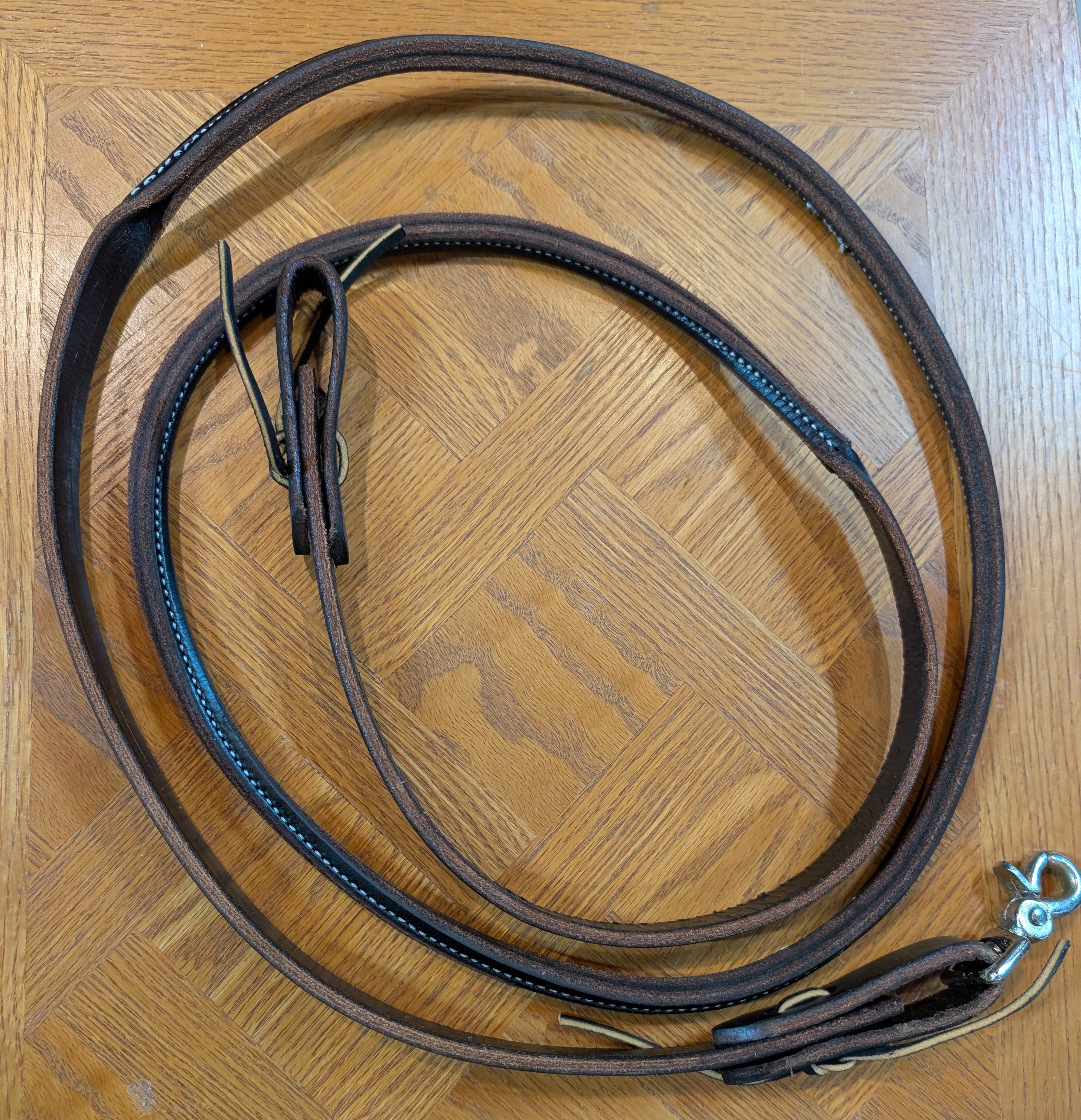 Brown leather rein on a wooden surface