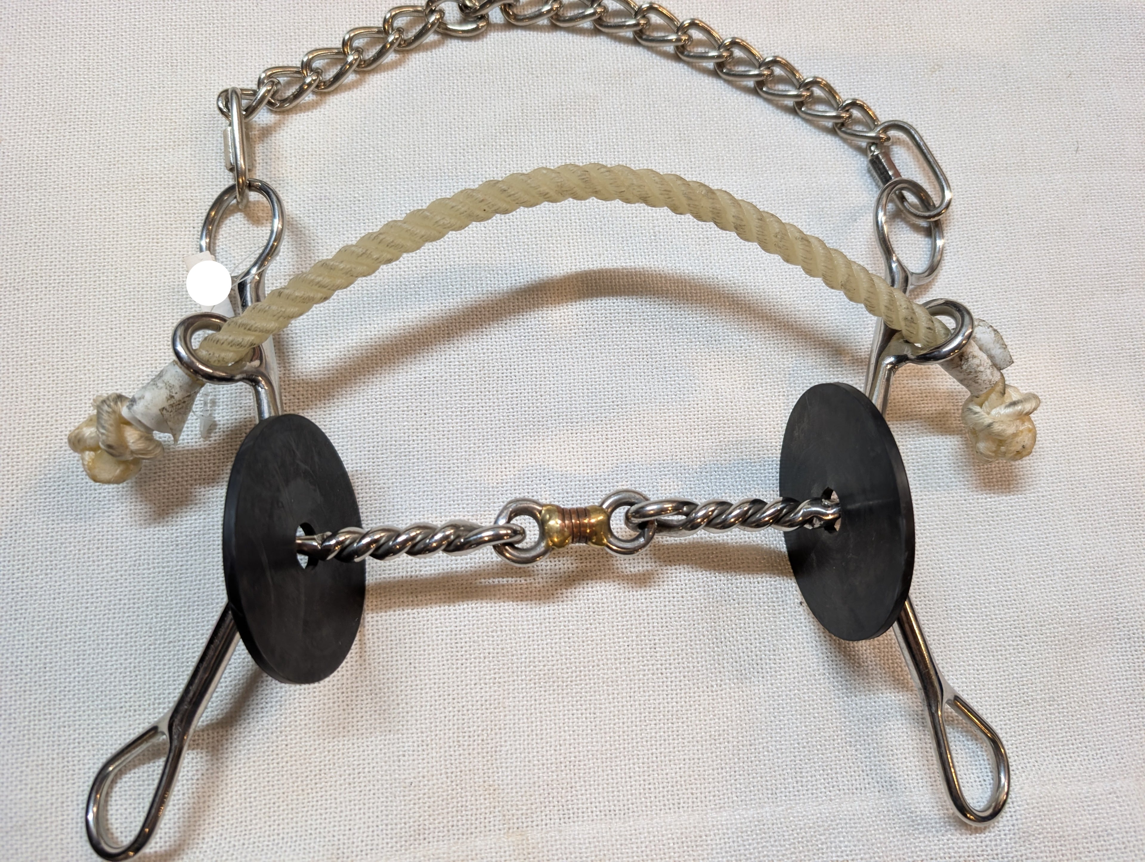 Metal bridle with black leather patches and a rope on a light background